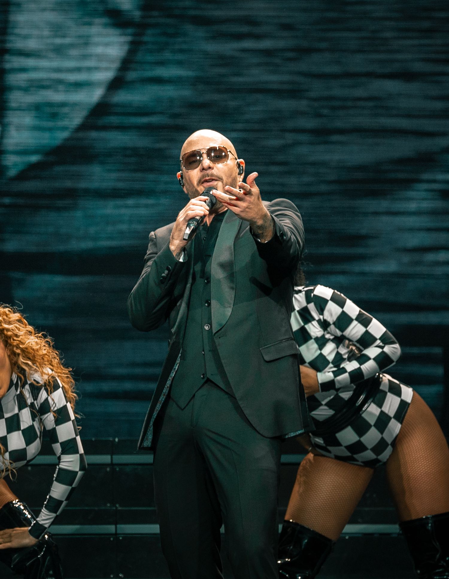 Stage performers in coordinated outfits deliver dynamic choreography against dark backdrop.