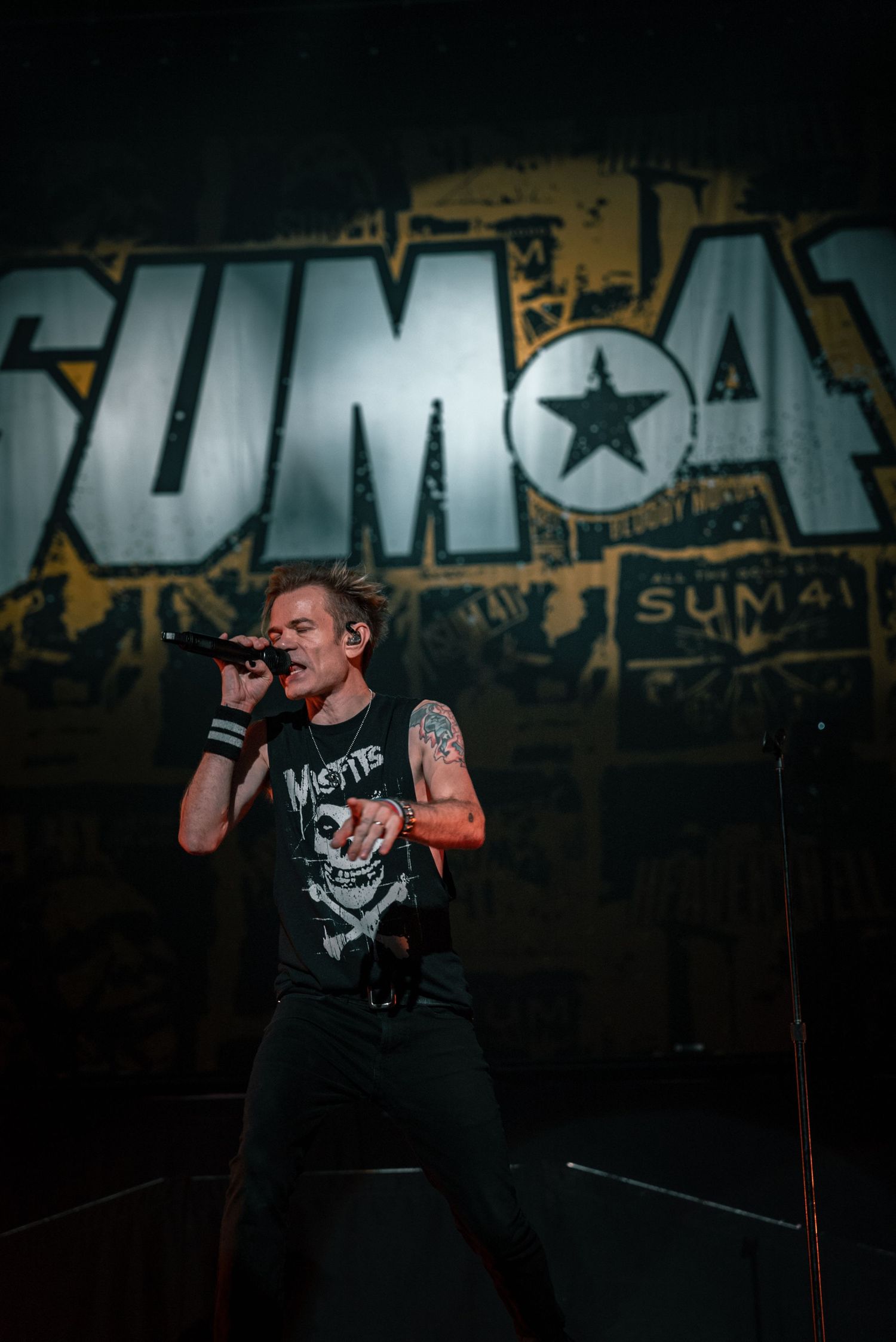Performer sings against large SUMA backdrop during high-energy concert.