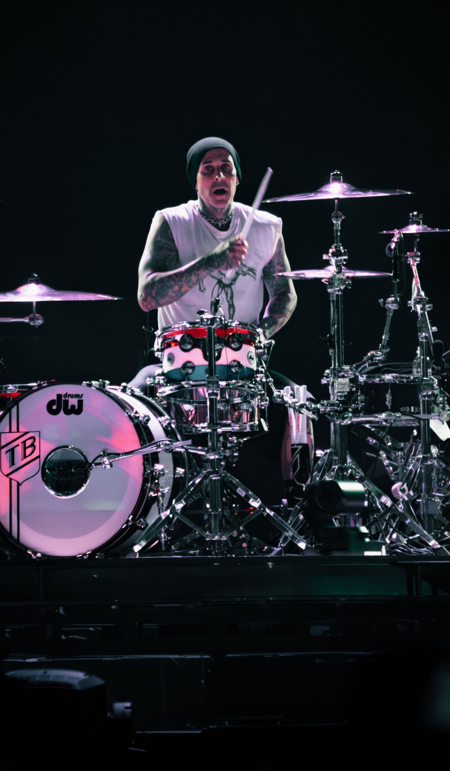 Multiple drum kits arranged on a dark concert stage with dramatic lighting.
