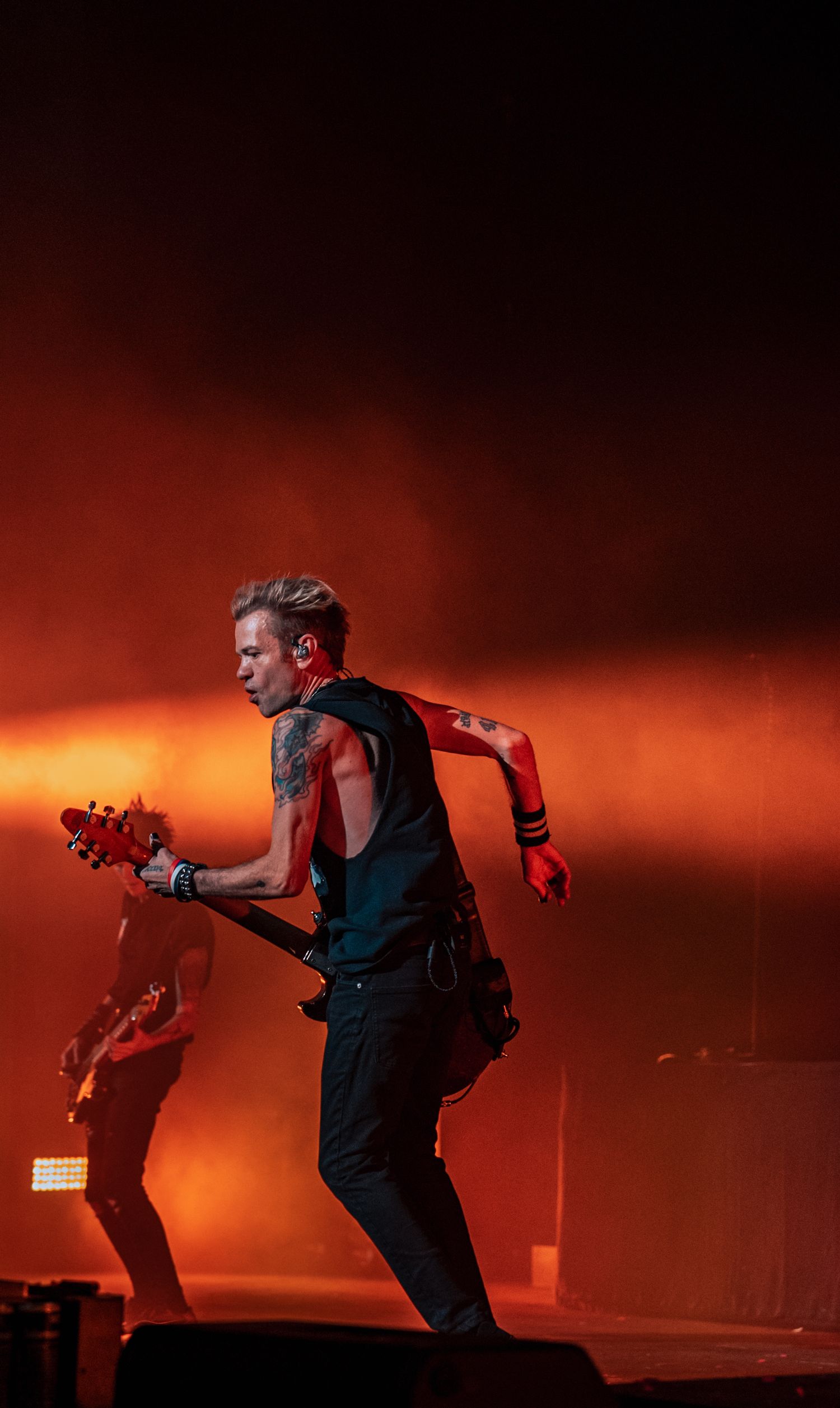 Rock band performing against fiery orange stage lighting creating dramatic silhouettes.