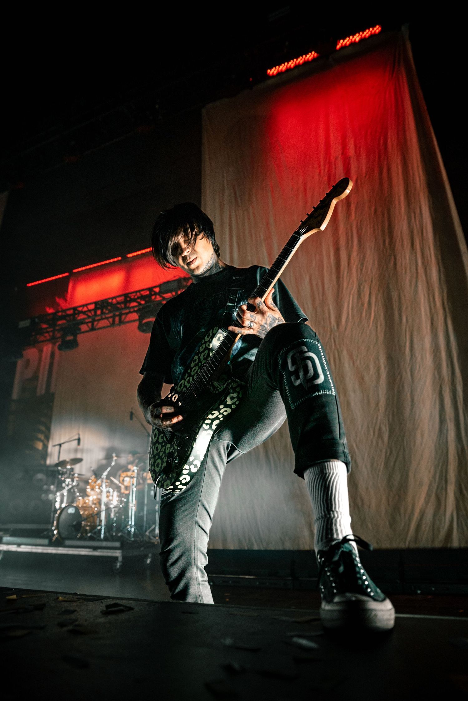 Dynamic concert performance with dramatic lighting showing energetic stage movements in black and white attire.
