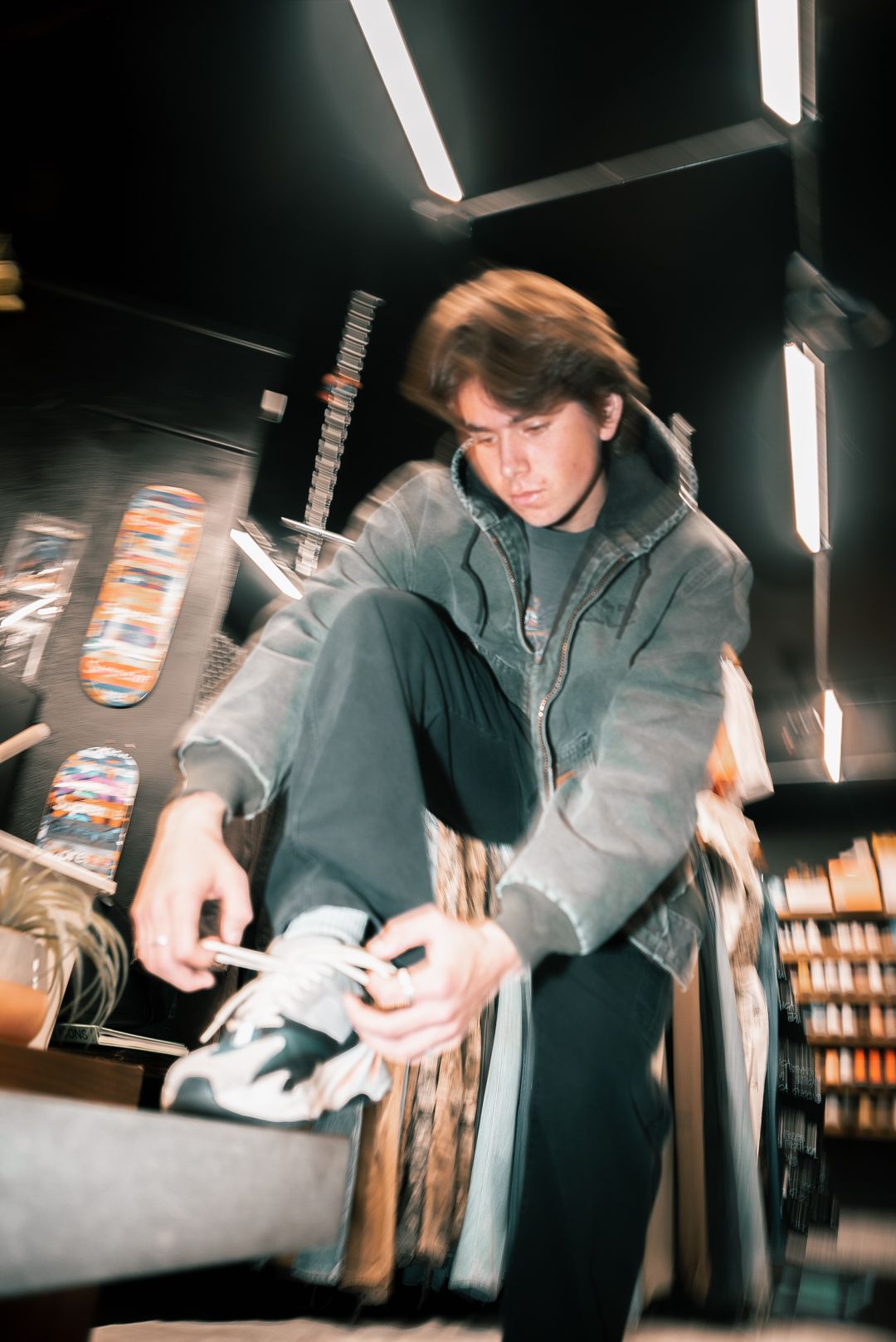 Person handling sneakers in retail store with overhead lighting.
