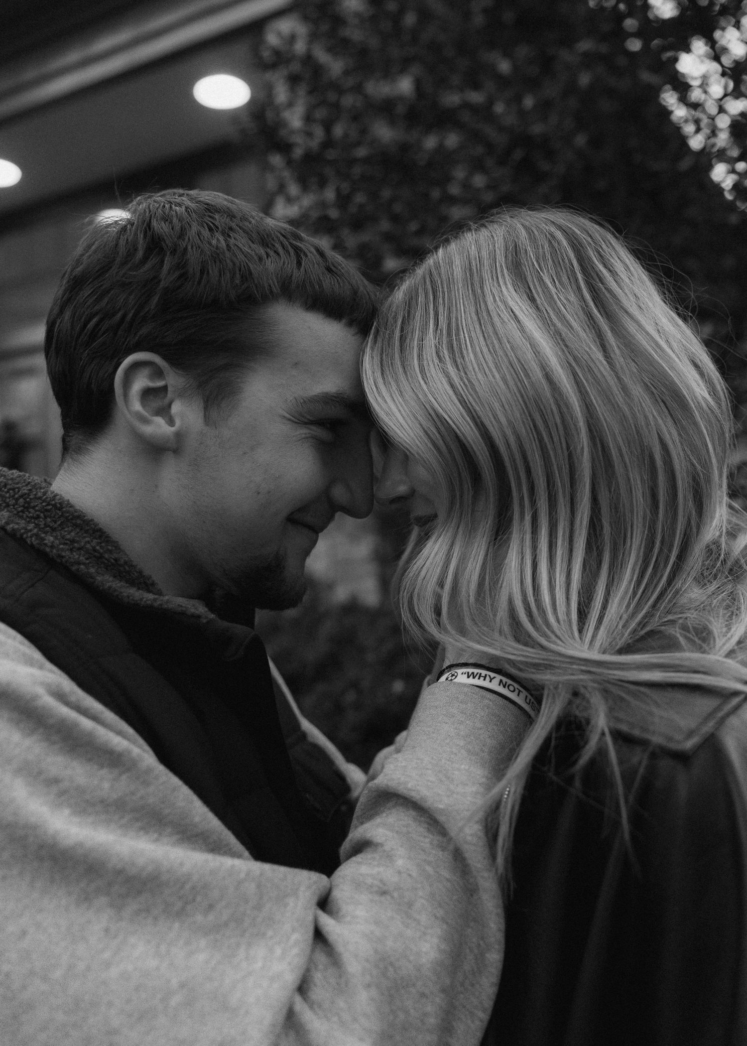 Intimate black and white close-up of a couple touching foreheads tenderly in a romantic outdoor night setting.