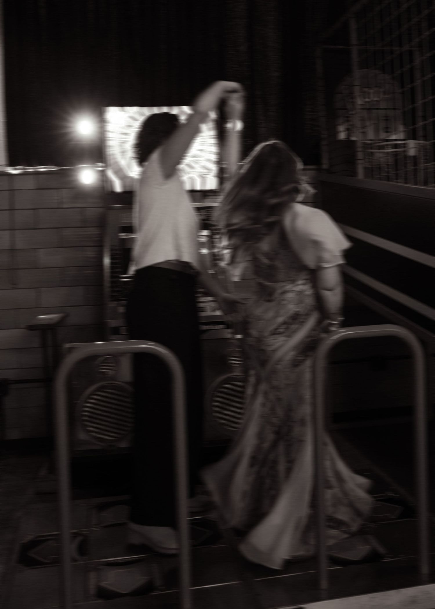 Couple dancing together in black and white photo at an outdoor venue at night.
