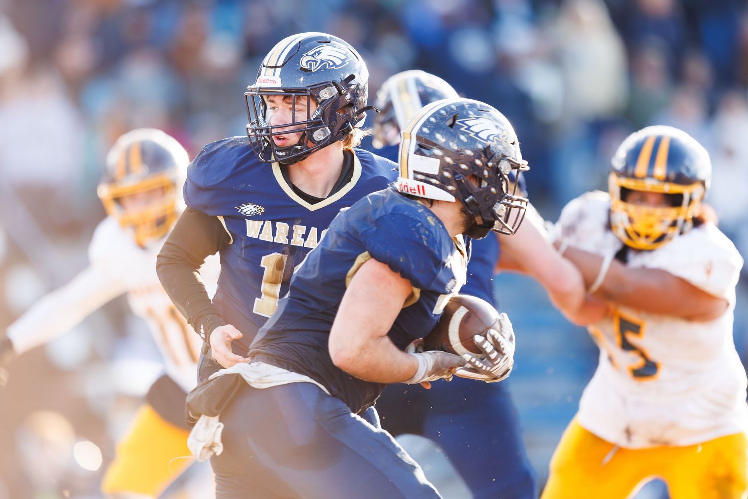 Football players from opposing teams clash during an intense play on the field.