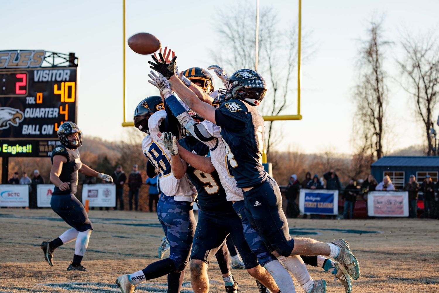 A football player catches a pass during a game while another player attempts to defend.