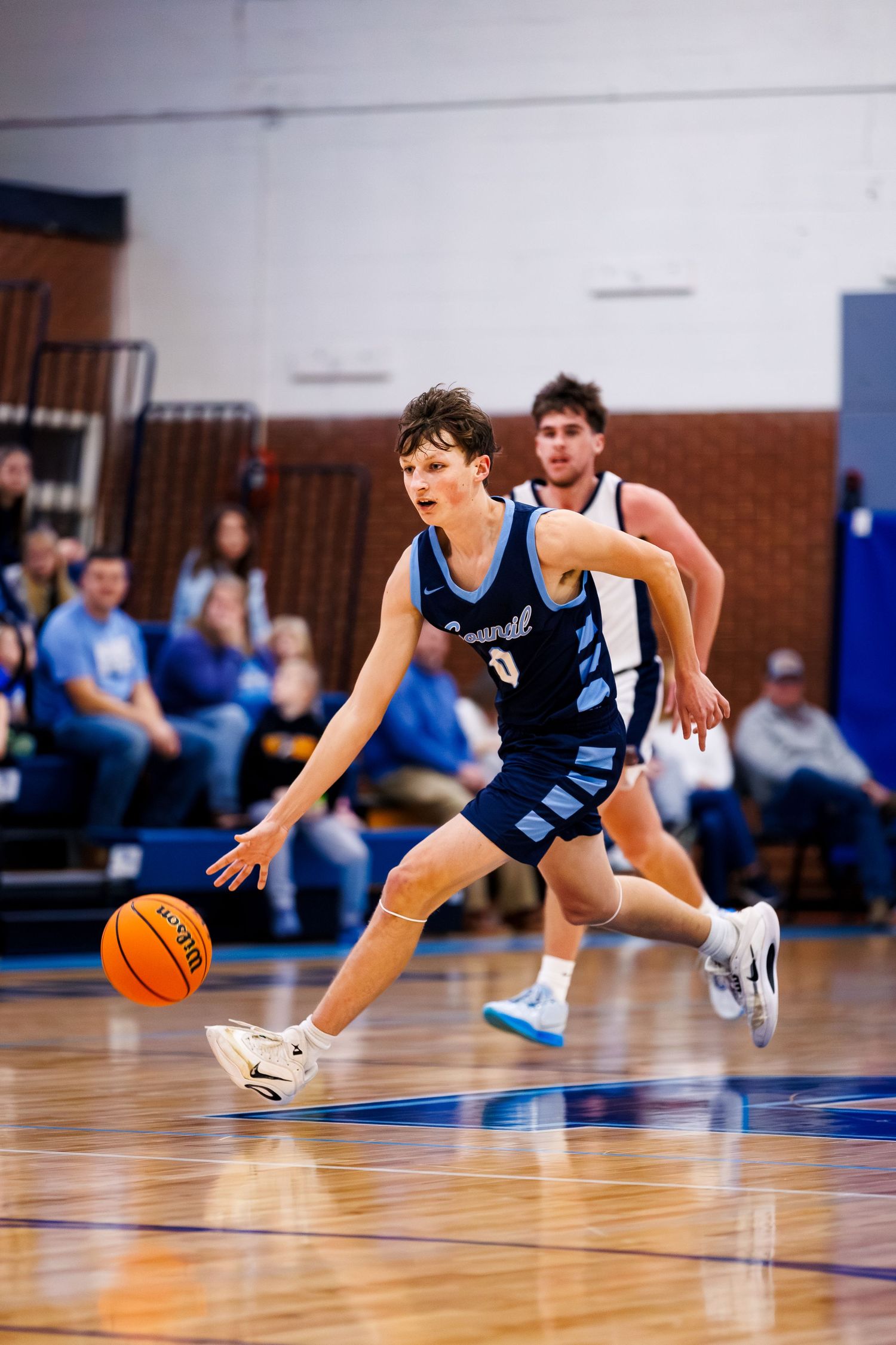 Basketball player diving for loose ball on hardwood court during intense game action.