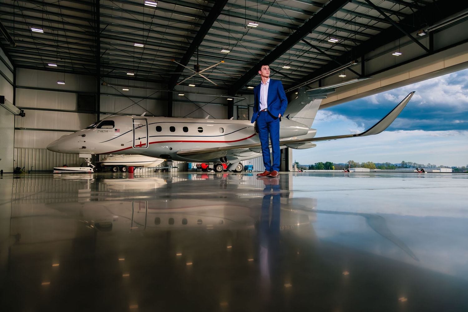 Business executive standing confidently next to private jet in hangar with reflective floor.