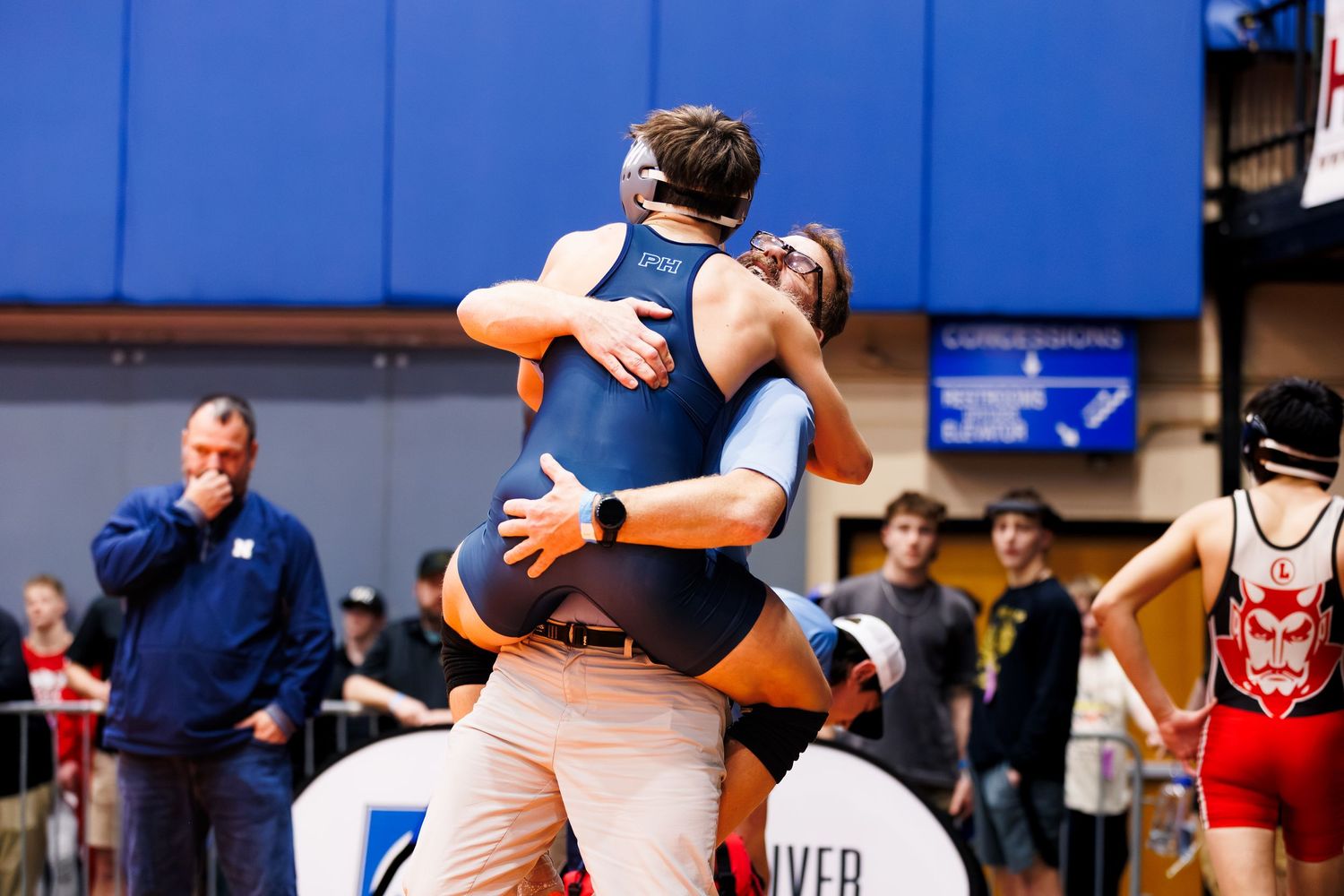 Wrestlers compete in a series of intense matches on blue wrestling mats during a tournament.