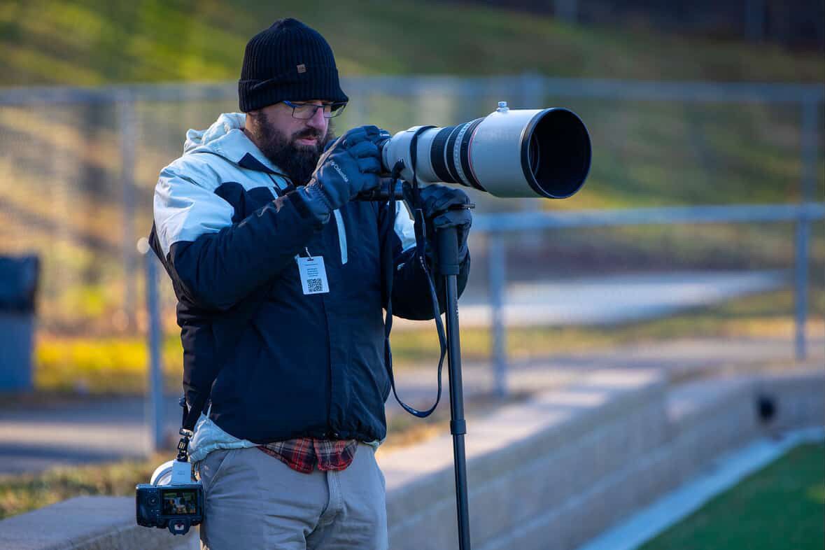 Sports photographer with professional camera equipment captures action shots.