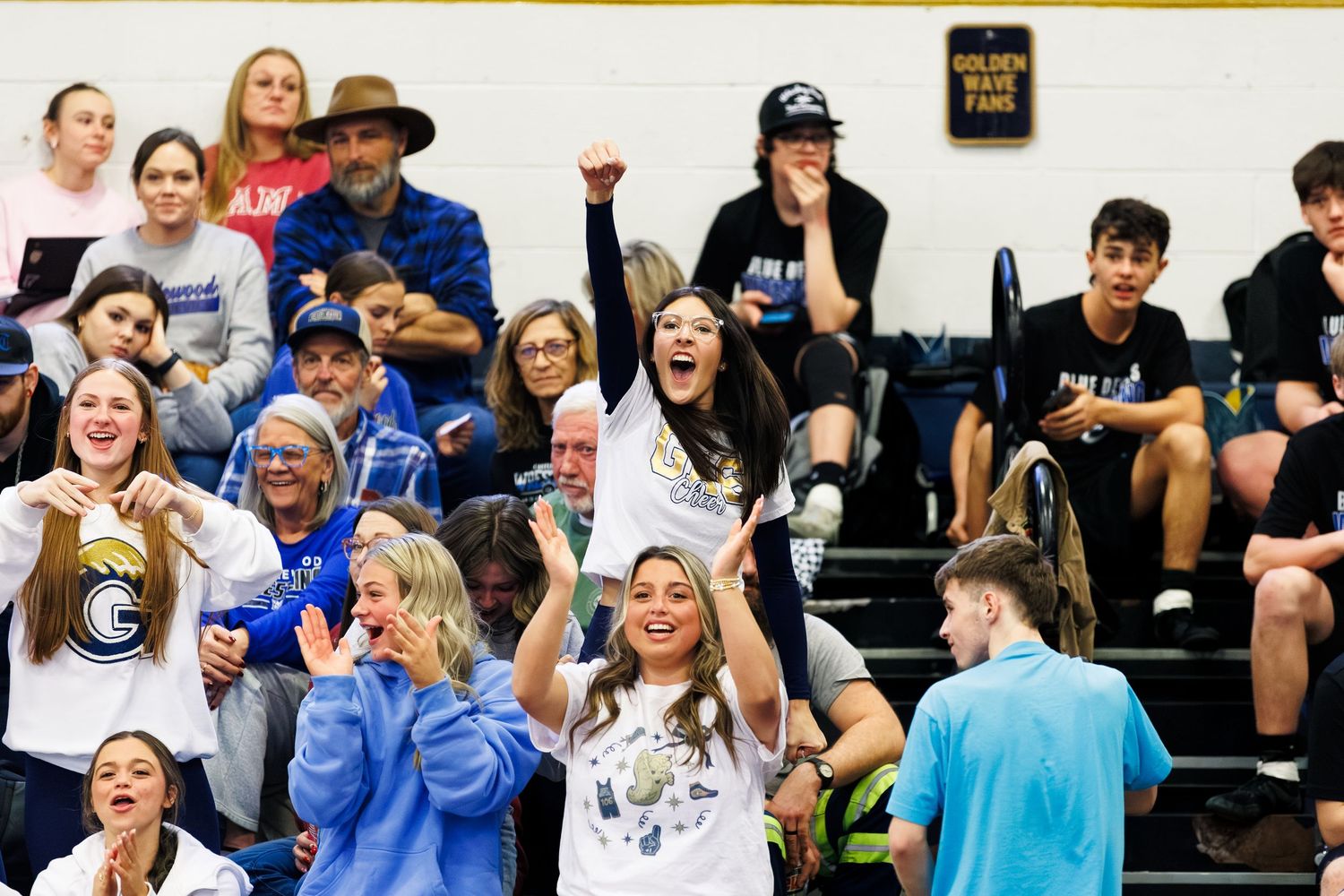 Enthusiastic crowd of spectators cheering from bleachers at a sporting event.