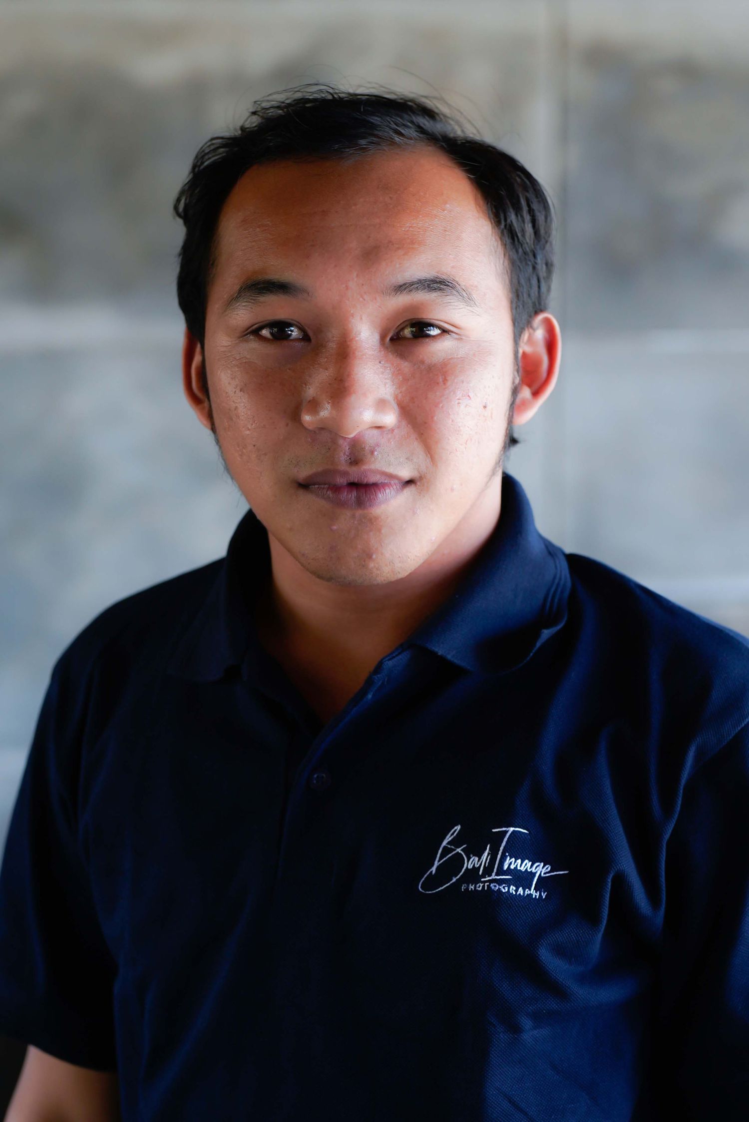 Candid portrait sequence showing various expressions in navy polo shirt against grey wall.