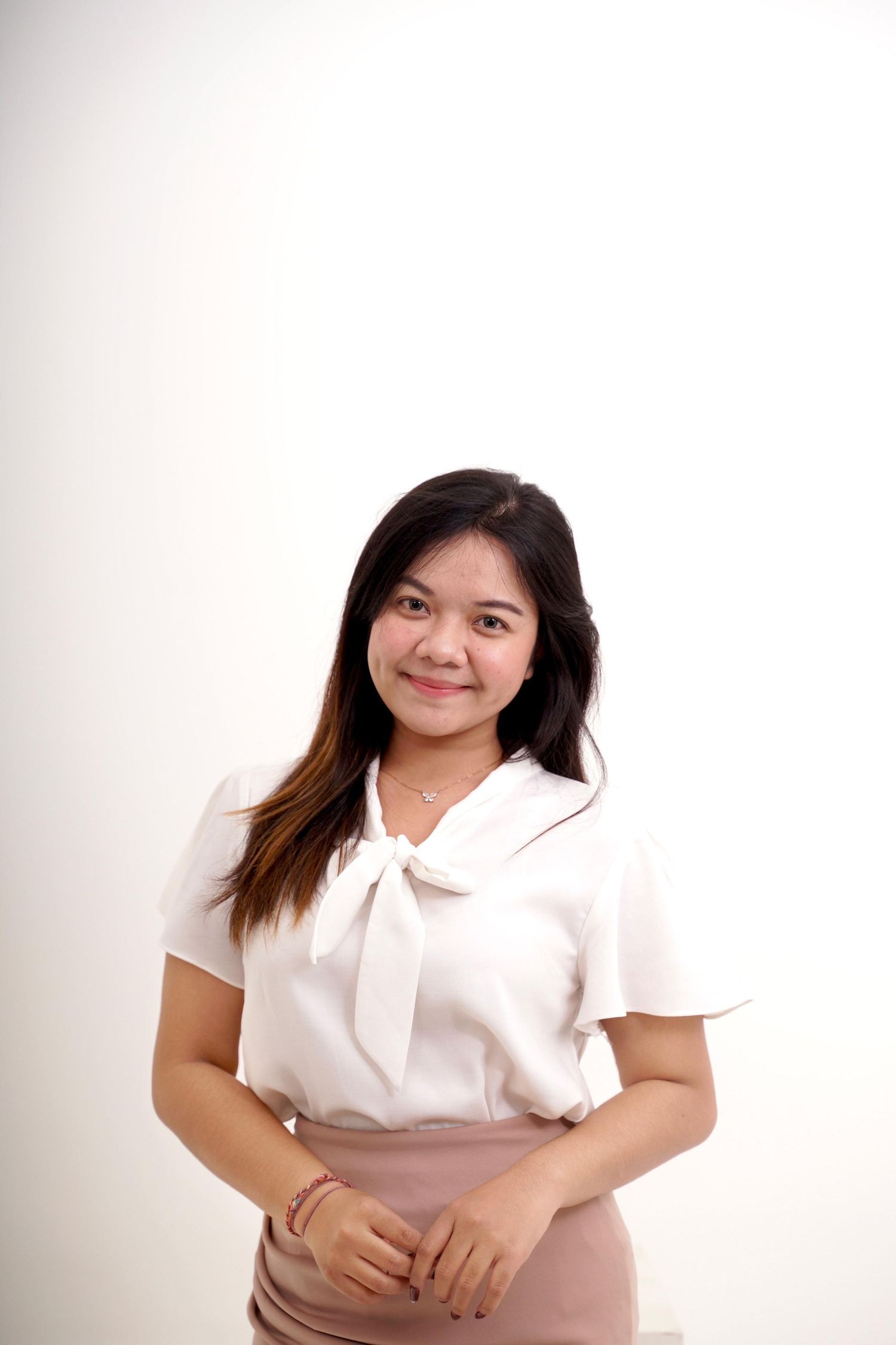 A person in a white collared shirt poses against a white background with a gentle smile.