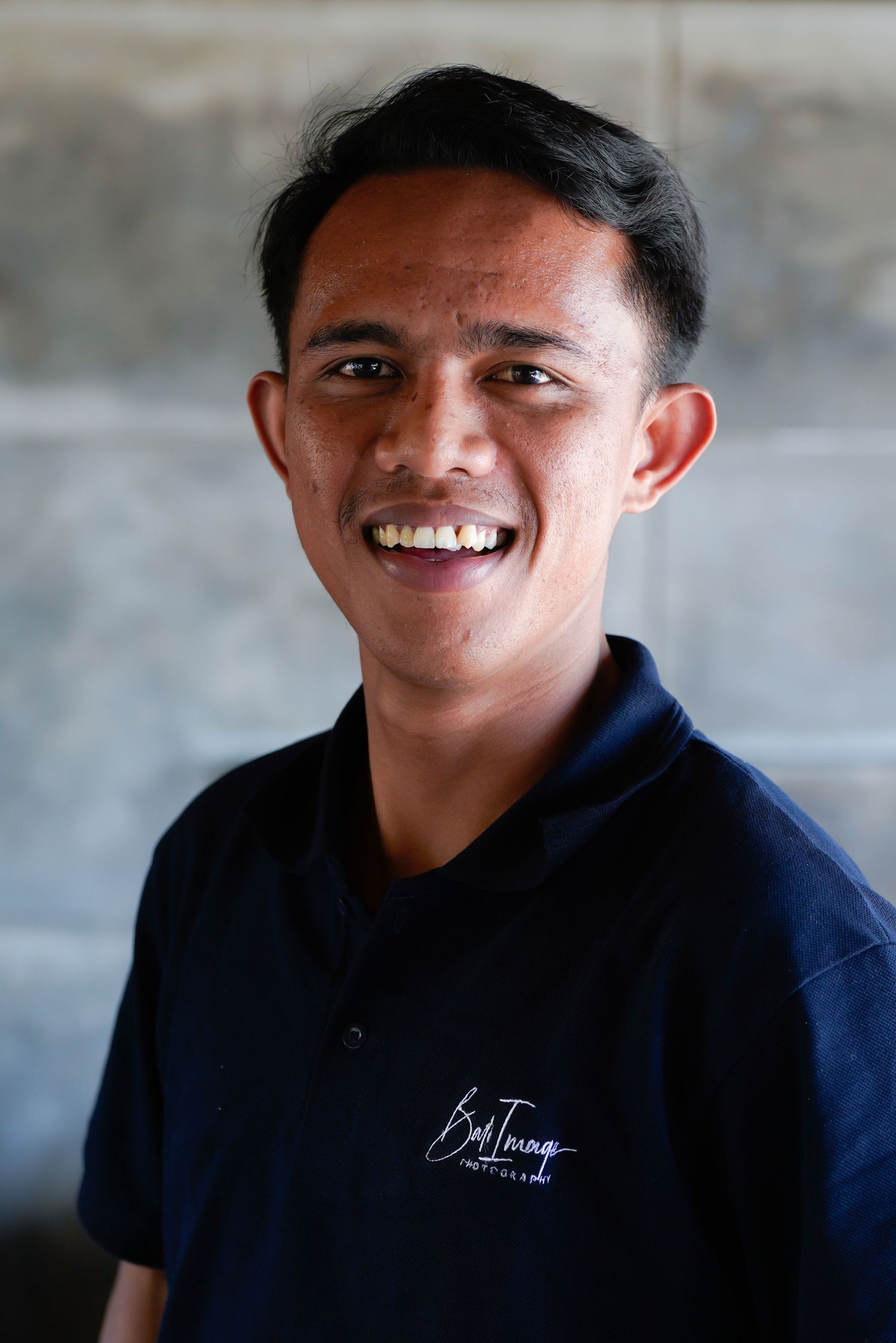 Professional photo series capturing natural expressions in dark uniform against grey wall.