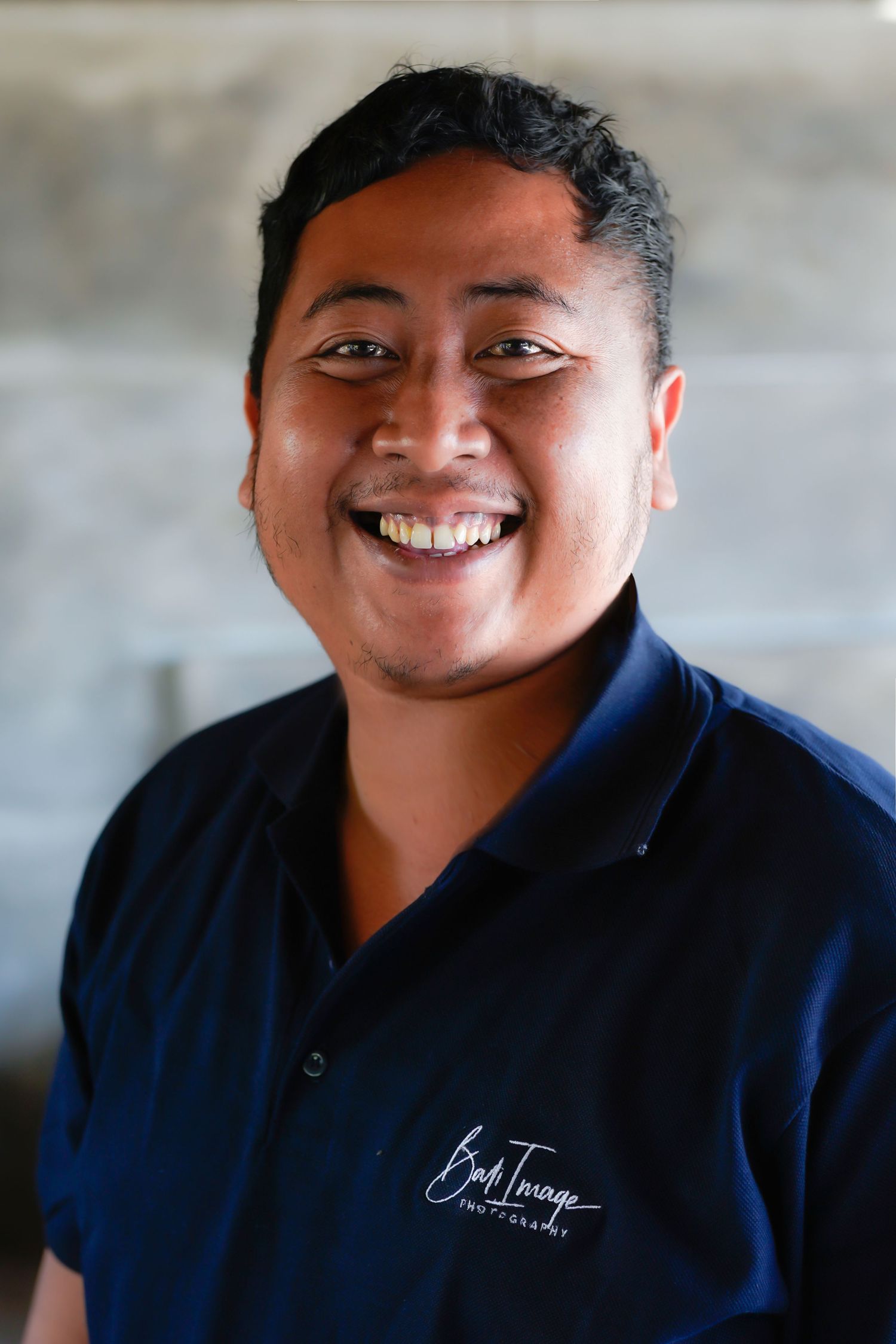 Professional headshot series showing warm smiles and navy blue uniform against concrete background.