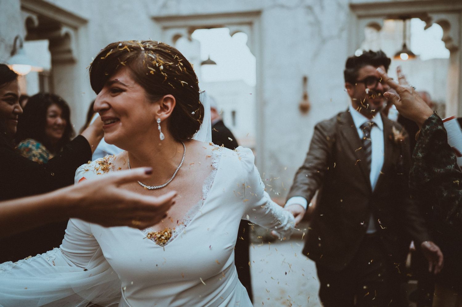 Wedding celebration with guests enjoying a joyful moment against white marble walls.