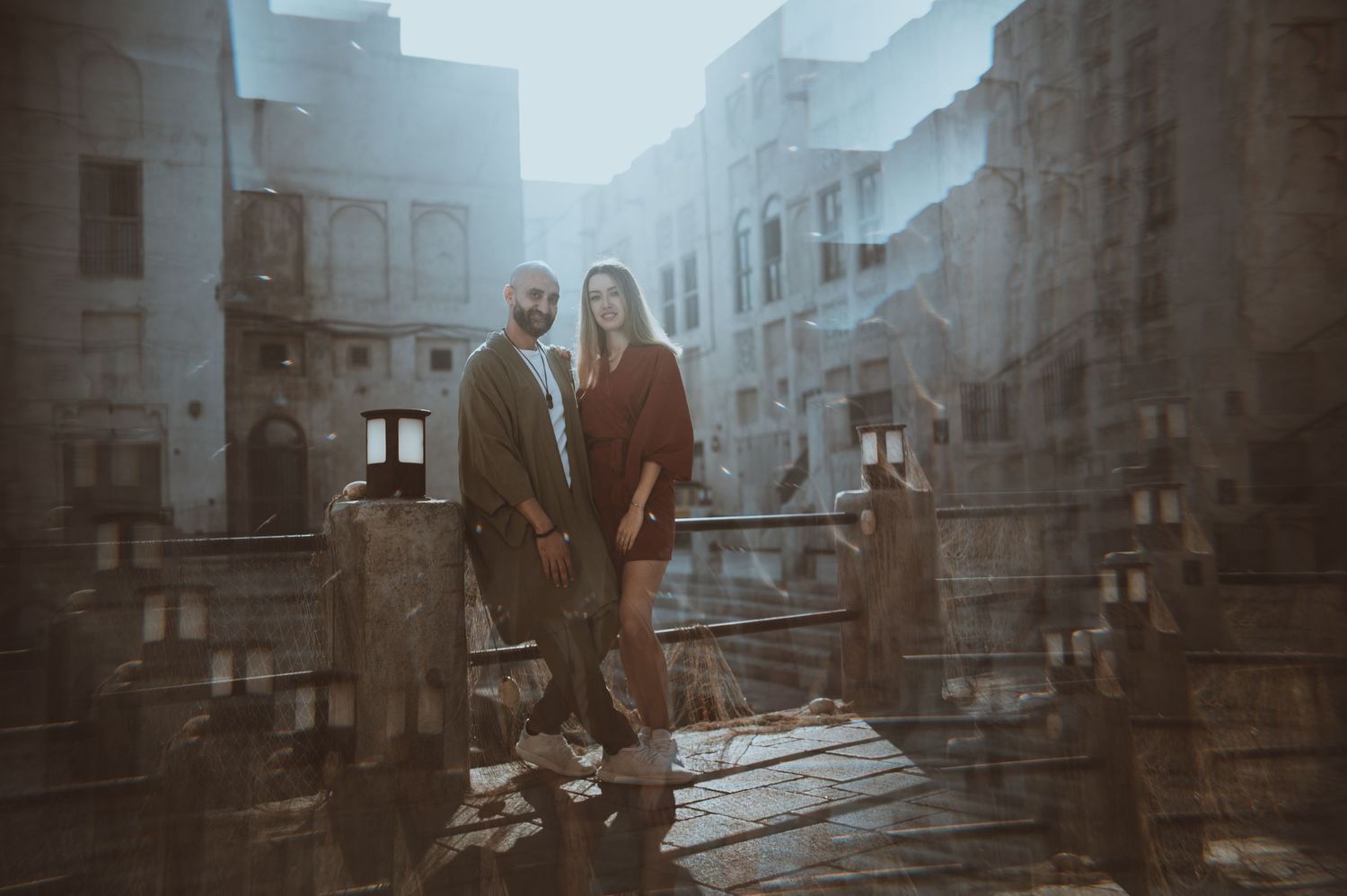 A couple explores an atmospheric stone corridor with dramatic lighting and architecture.