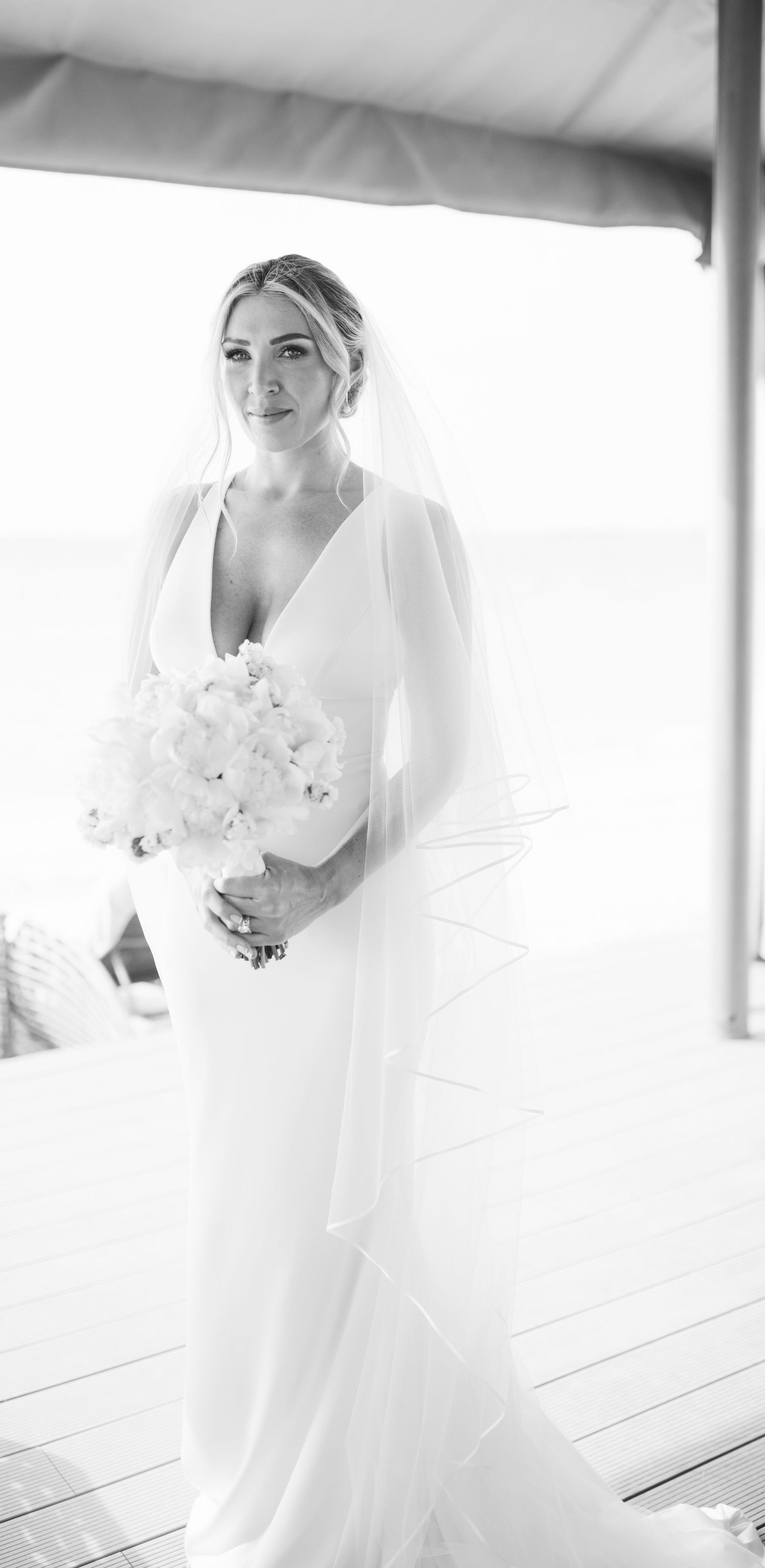 Ethereal bridal portrait in white with delicate veil and bouquet.