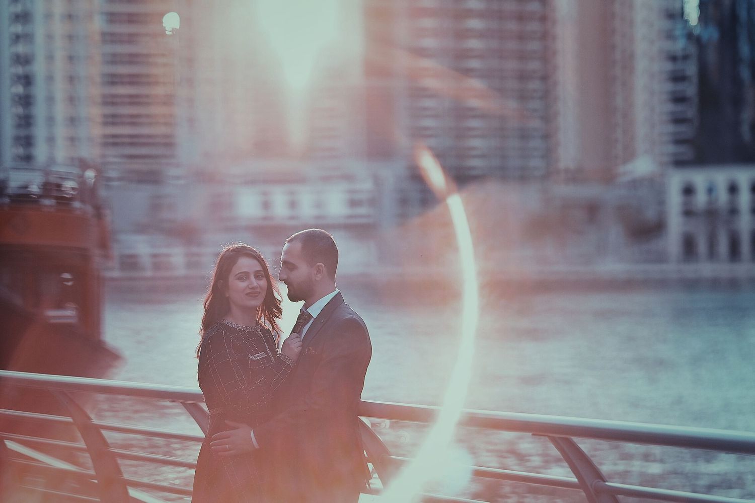 Romantic urban photoshoot with couple against city backdrop at sunset.