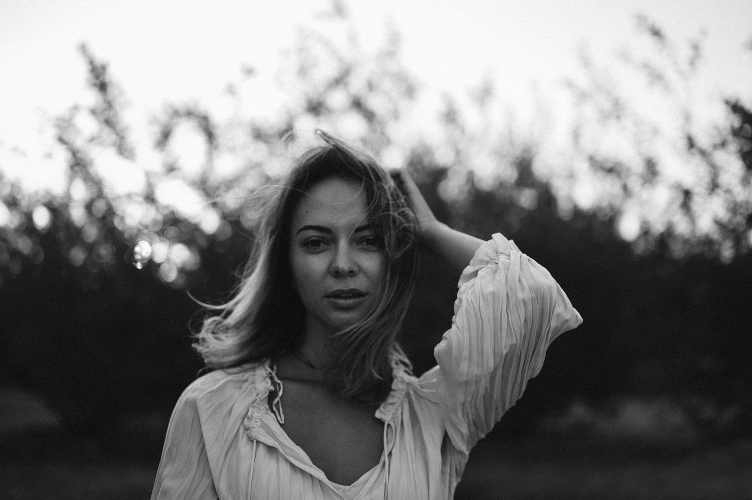A dreamy black and white portrait captured against a soft, bokeh background at sunset.