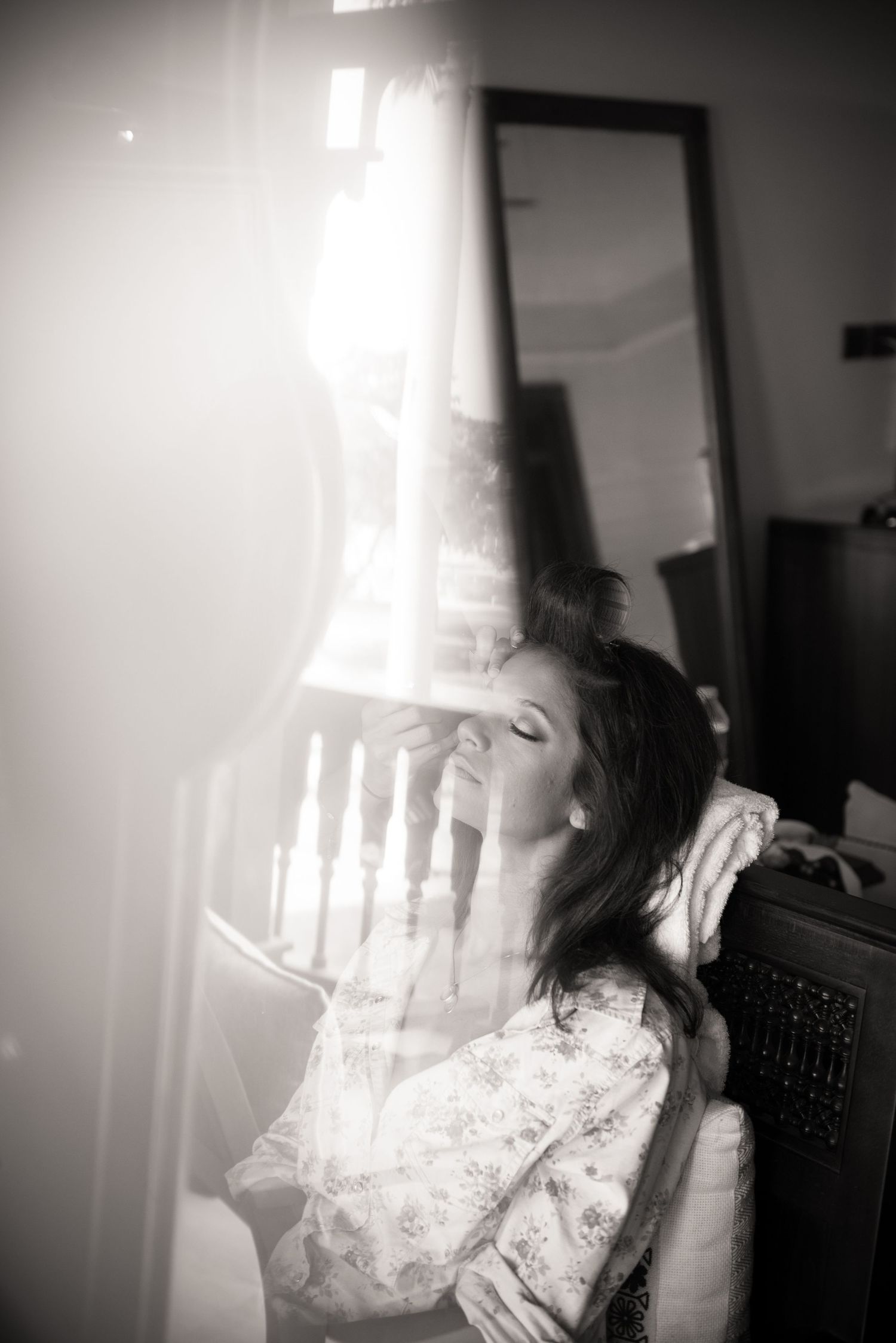 Artistic black and white portrait with dramatic window lighting.