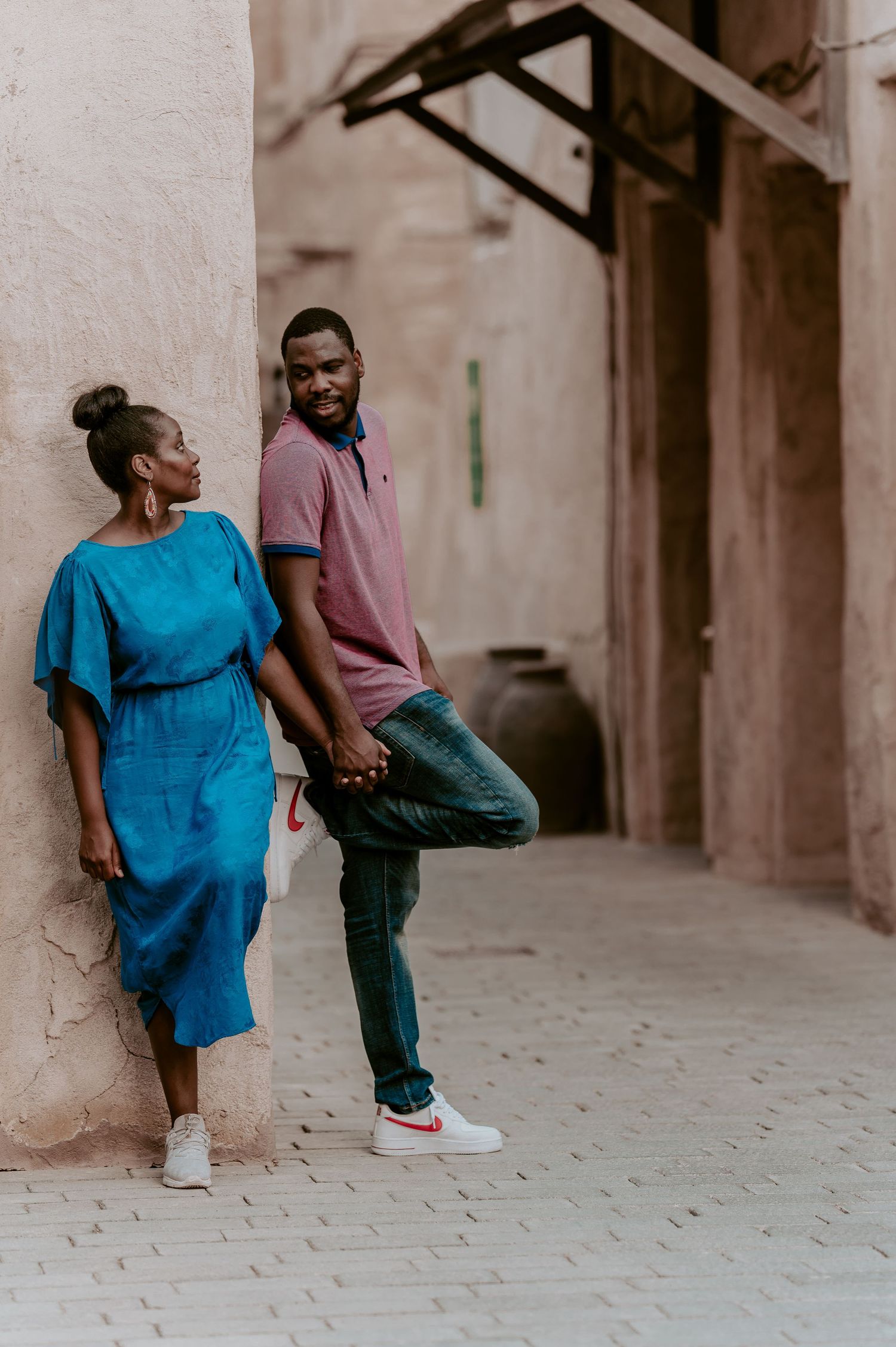Couple in blue and purple outfits sharing candid moments against an urban backdrop.