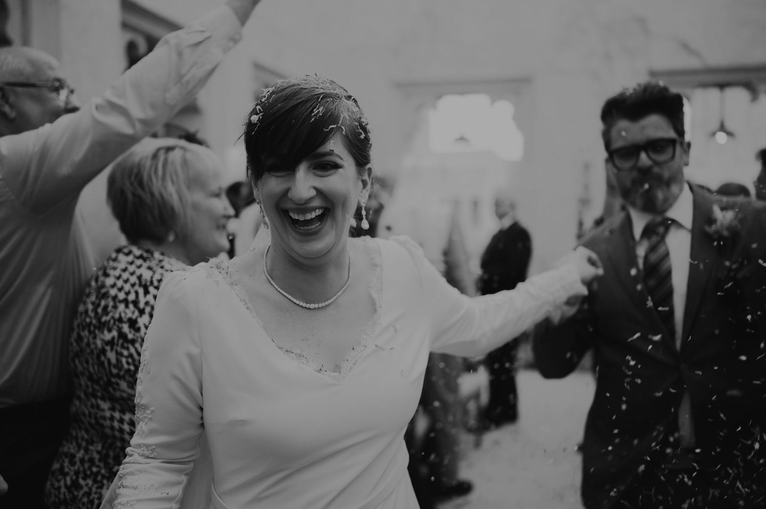 Black and white photo of wedding guests sharing laughter during a celebration.