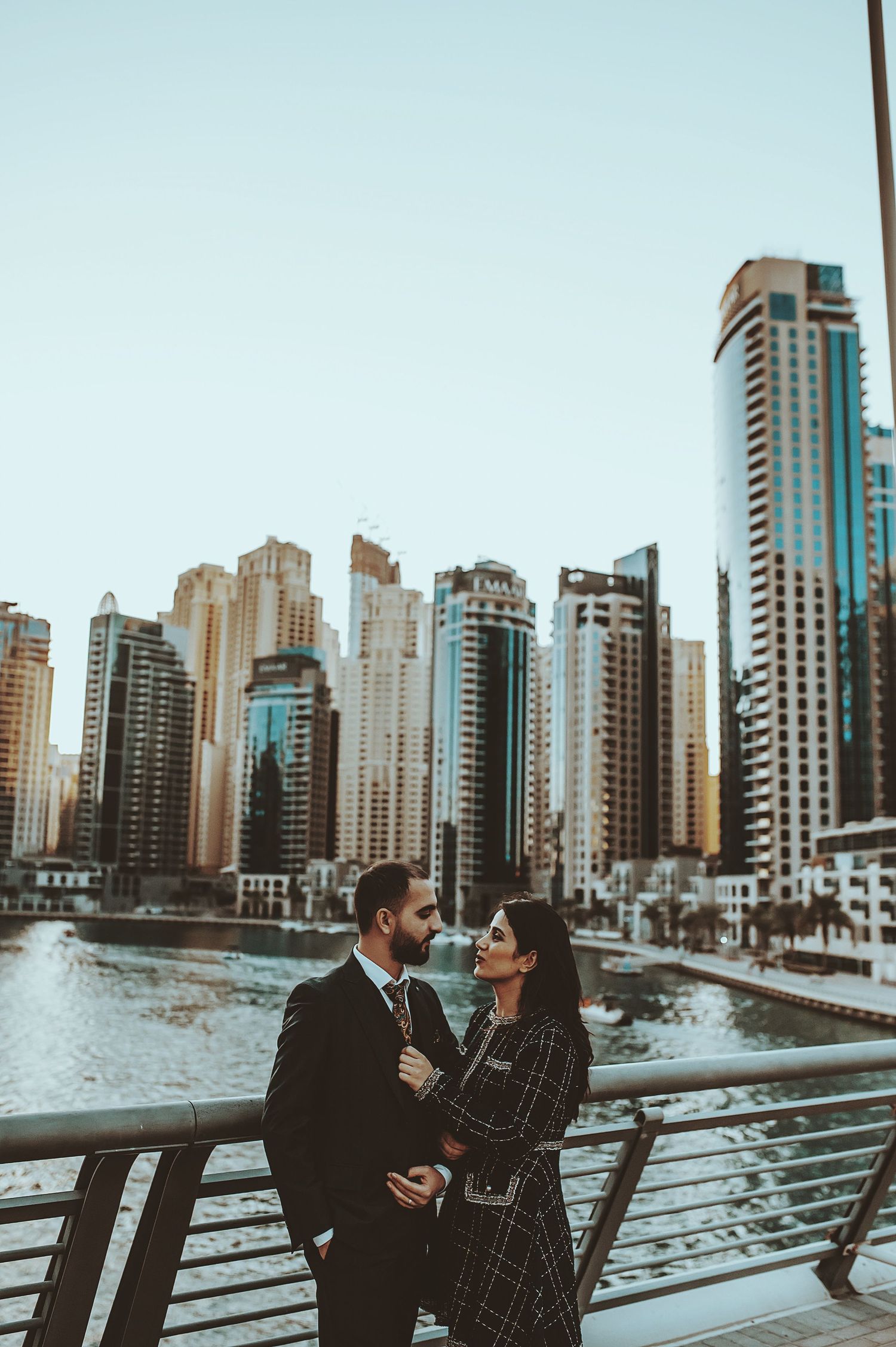 Stylish couple embracing against a backdrop of modern city skyscrapers.
