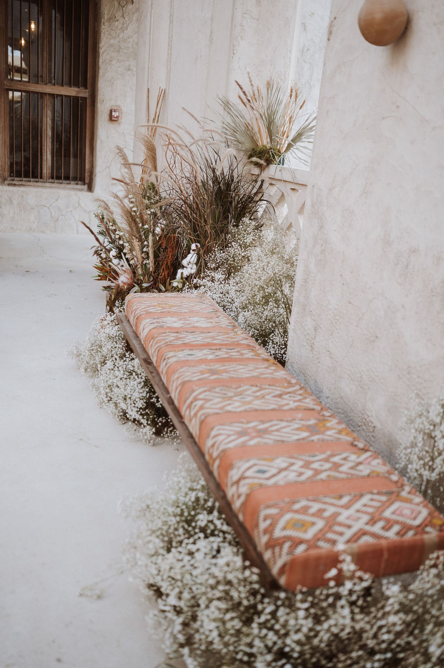 Orange patterned cushions with geometric designs decorate a rustic stone bench.