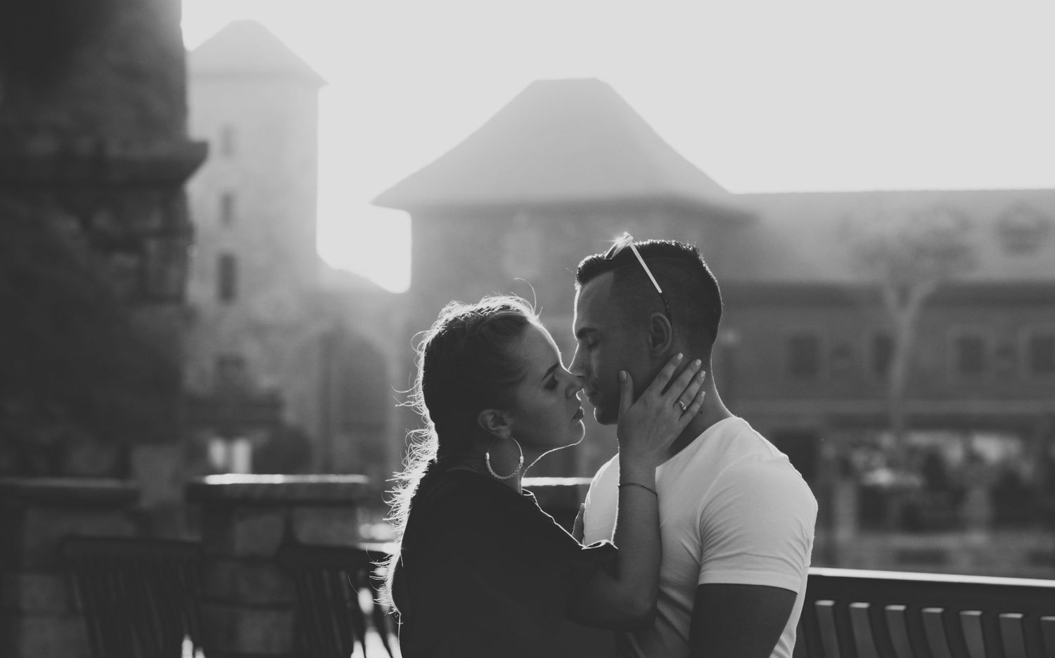 A black and white film strip showing a couple embracing in various romantic poses at sunset on a balcony.