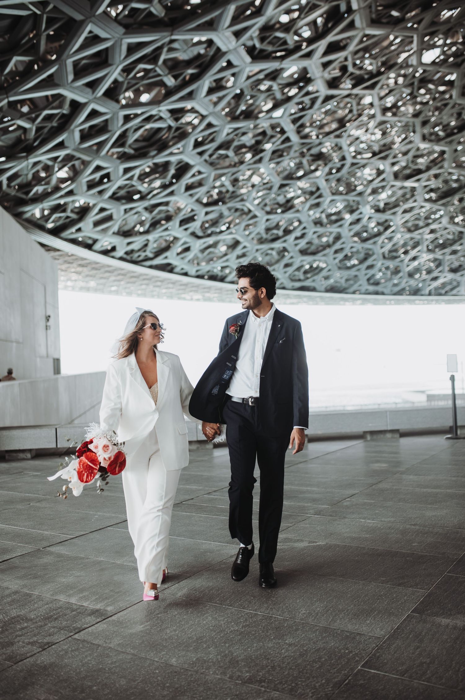 Modern architectural wedding photos with couple walking under textured ceiling.