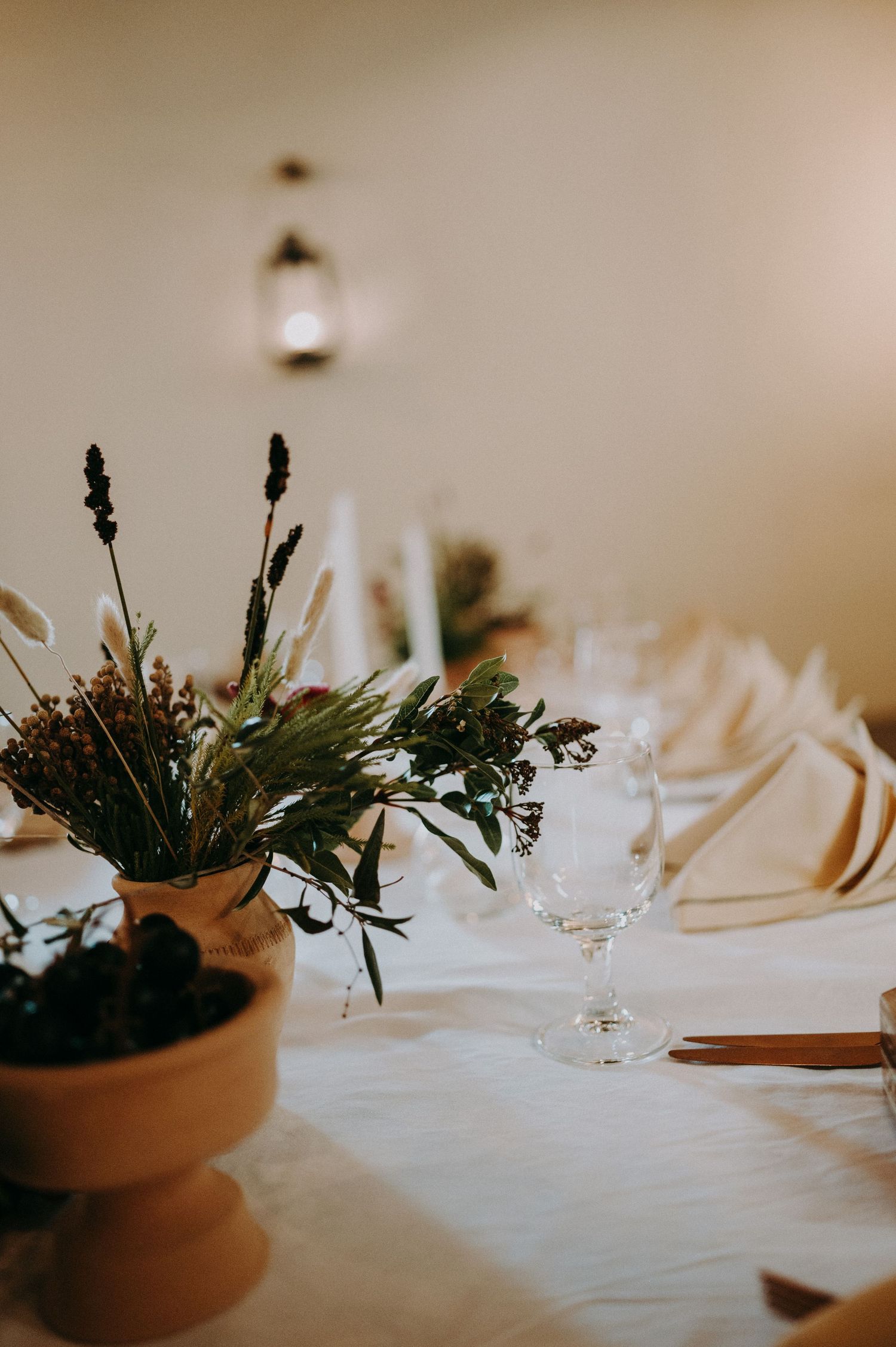 Elegant table settings with white linens and potted plant centerpieces at a wedding reception.
