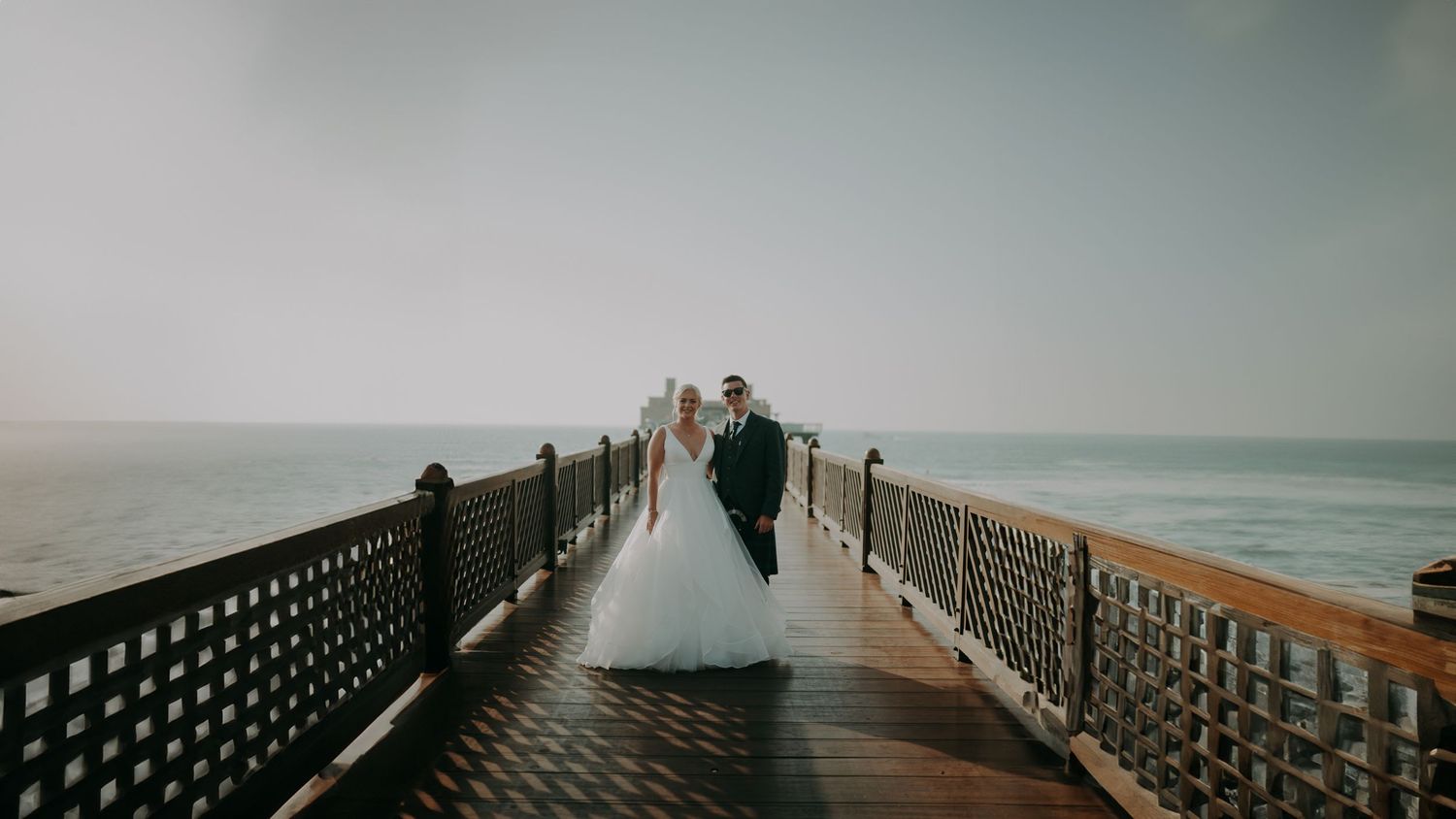 Panoramic view of a wooden boardwalk extending over water at sunset.