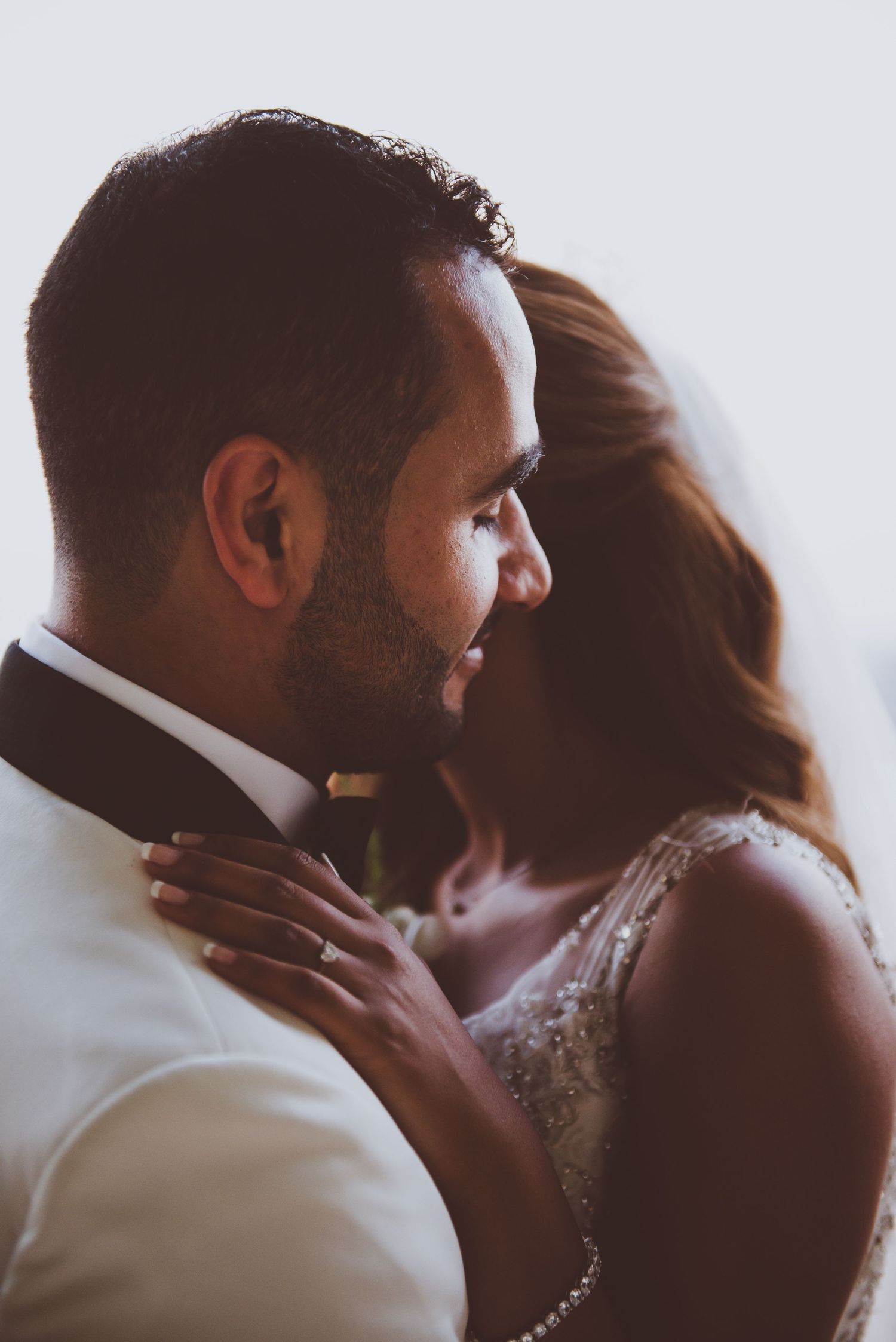 Silhouetted wedding couple sharing a tender moment in soft window light.
