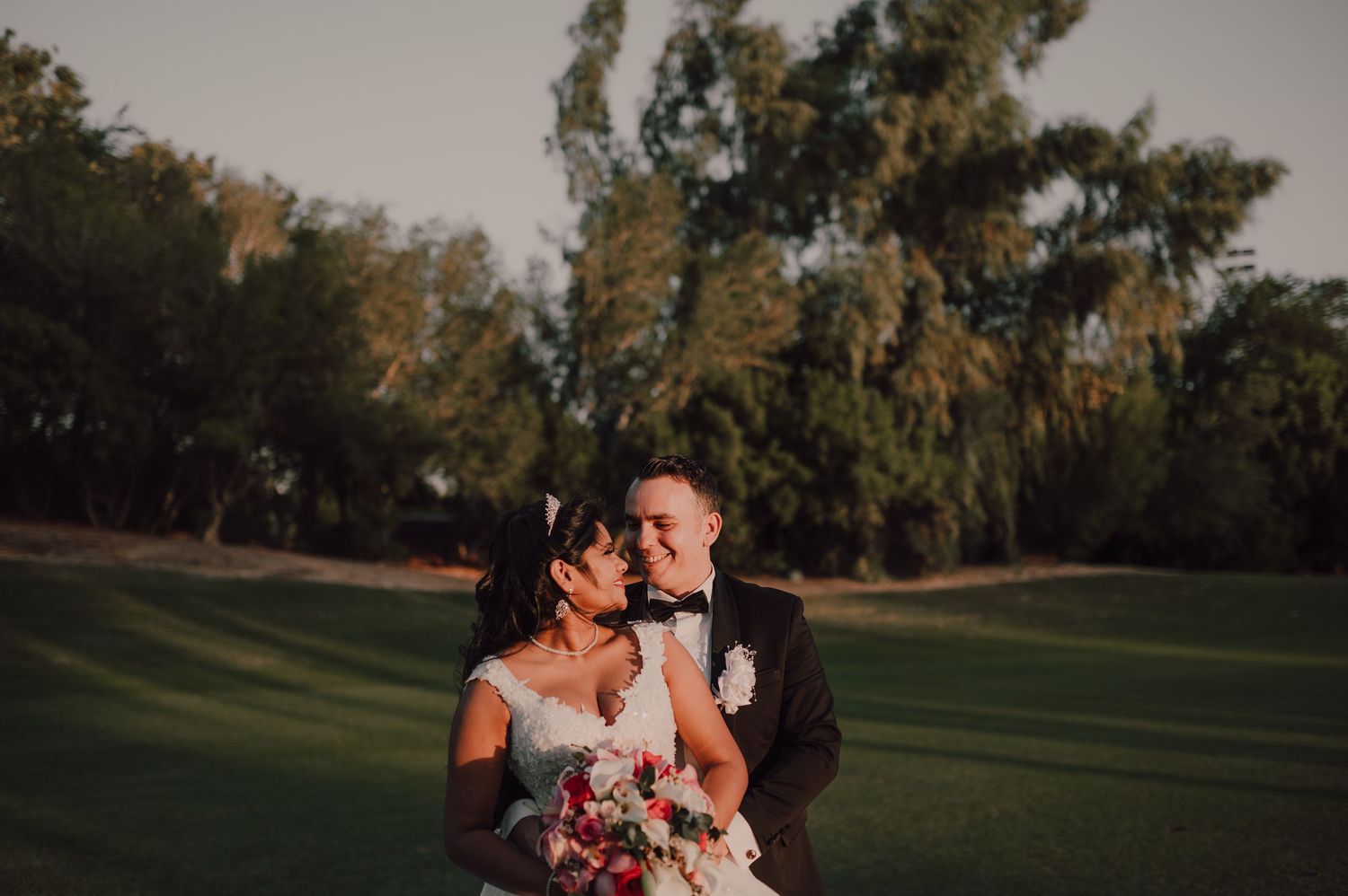 A romantic outdoor photoshoot at sunset with trees in the background.