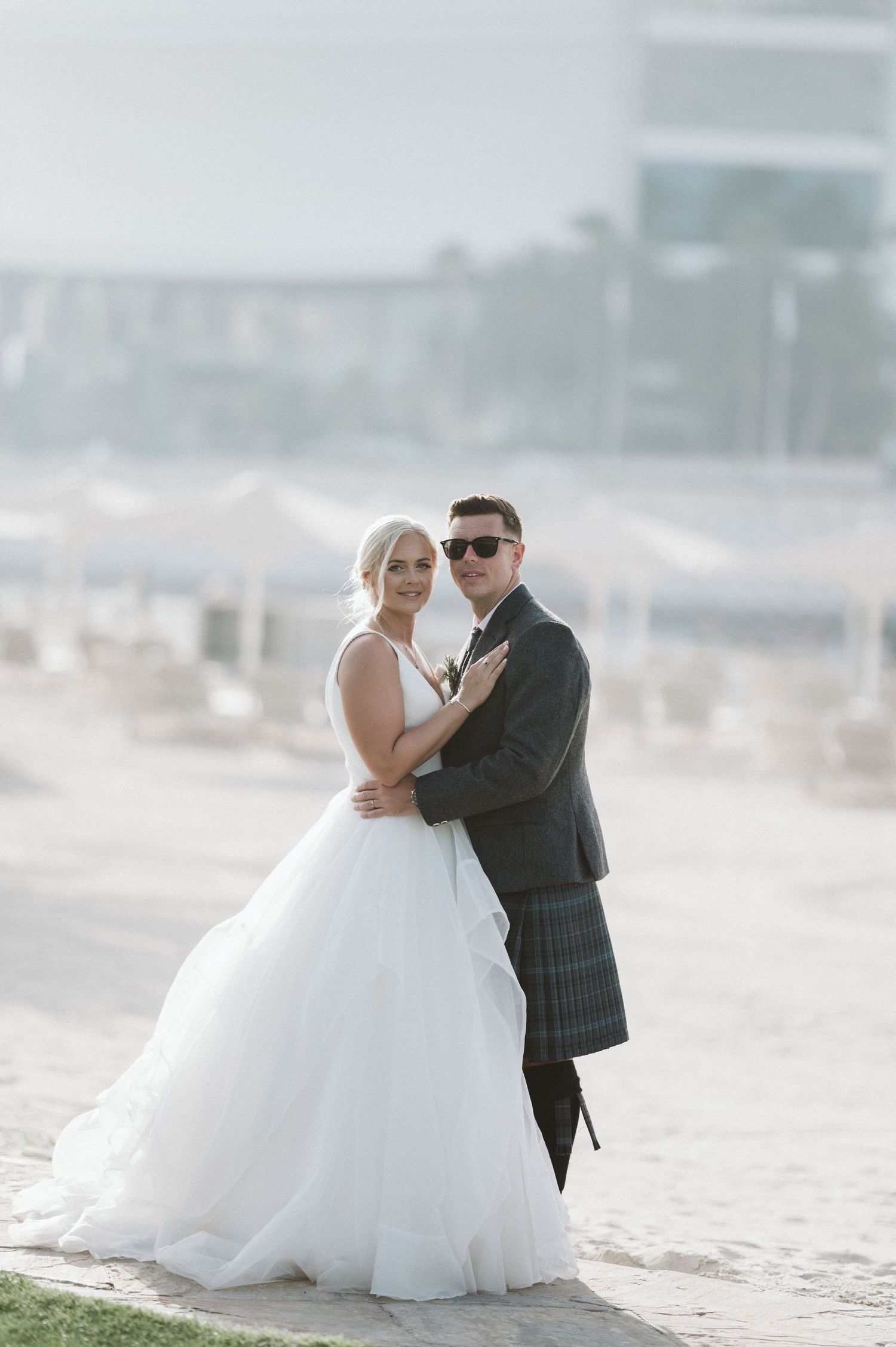 Wedding couple poses together on a misty beach with soft natural lighting.