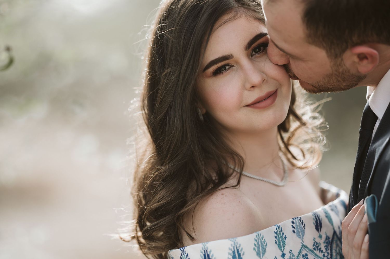 Intimate wedding portrait featuring an off-shoulder white gown with delicate blue pattern details.