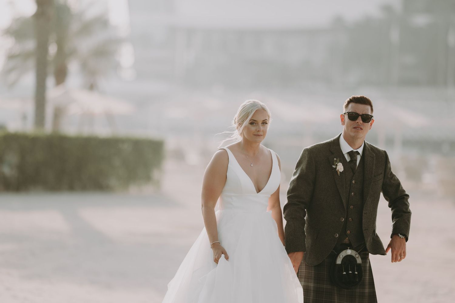 Newlyweds dance together on a sandy beach with soft dreamy lighting.