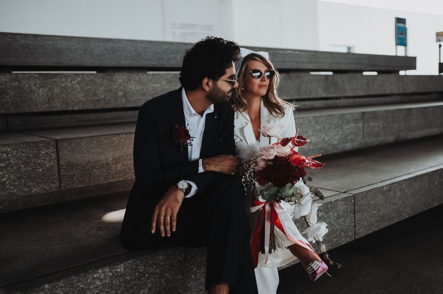 Wedding couple shares intimate moments on urban concrete steps in dramatic lighting.