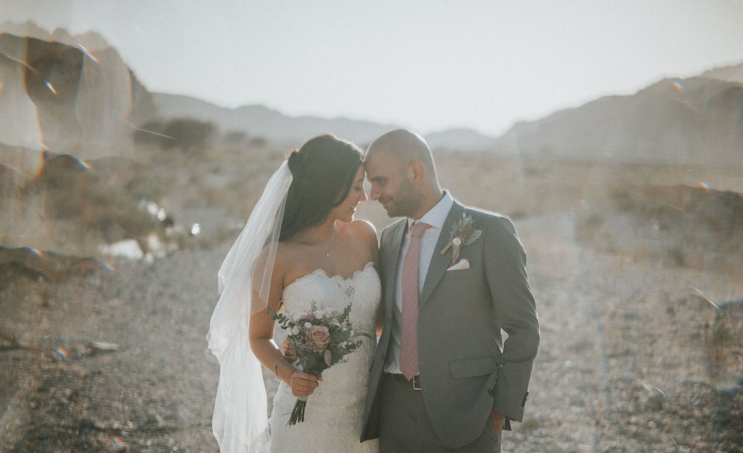 Wedding ceremony in mountainous desert landscape with soft lighting.