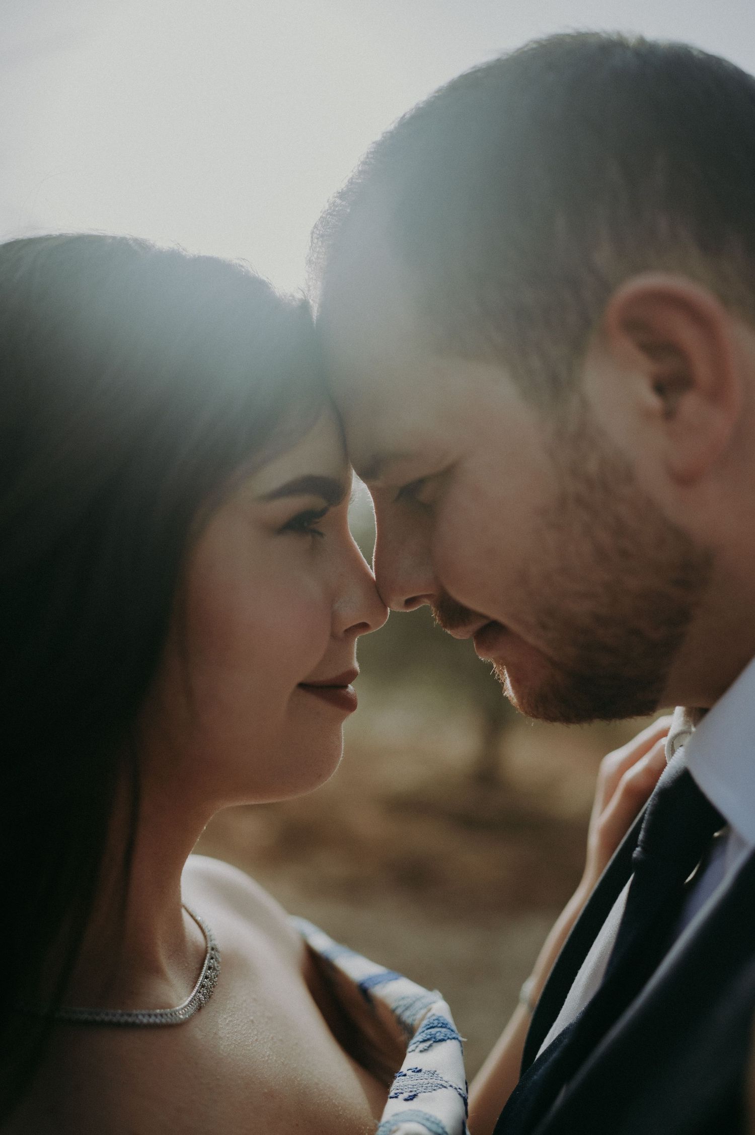 Intimate close-up portrait of couple in formal wear against natural lighting.