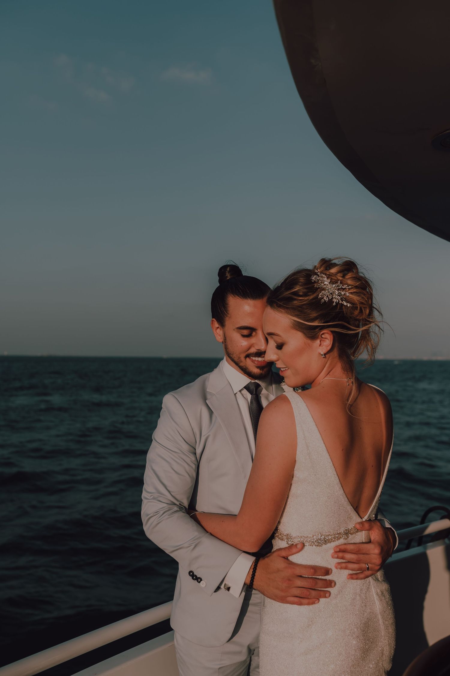Couple embracing on a boat during sunset over the ocean.