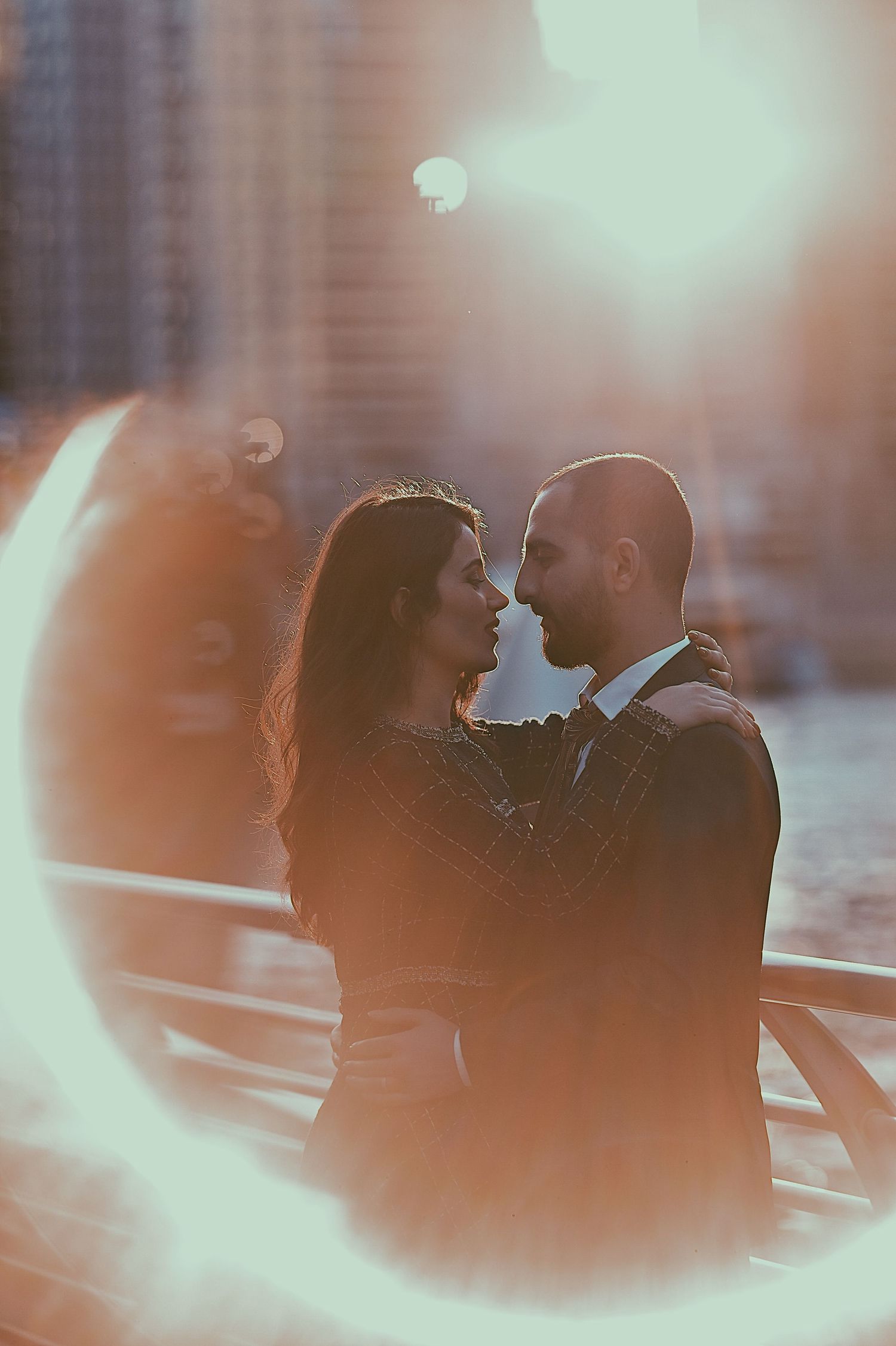 Romantic silhouette of couple sharing intimate moment against urban backdrop with soft bokeh lights.