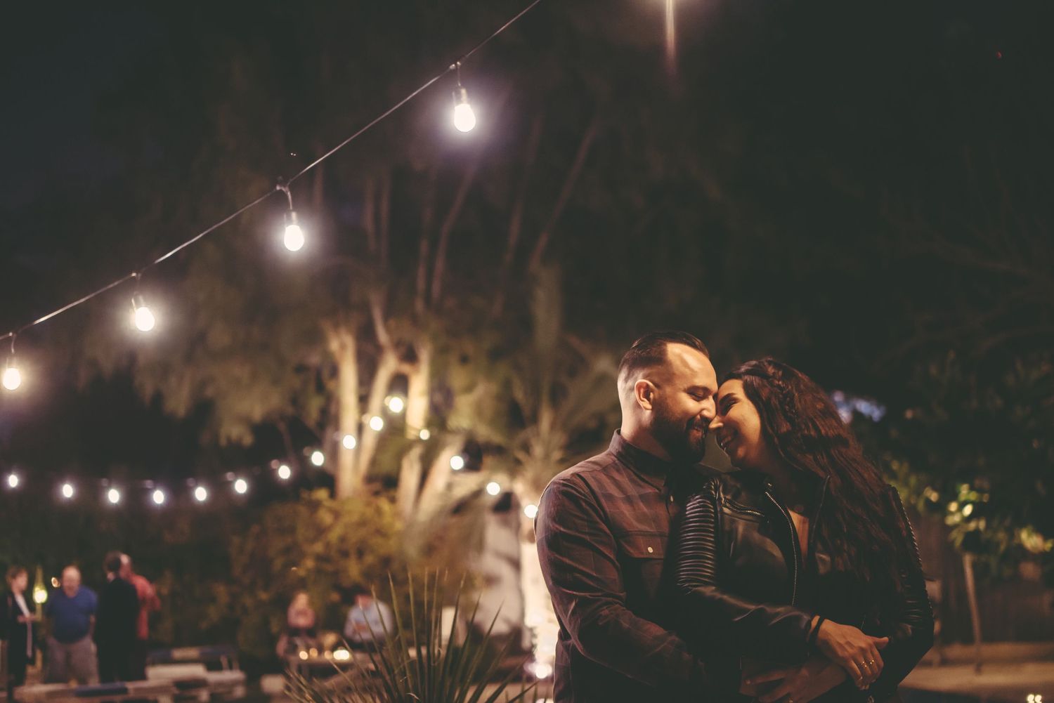 String lights glow against a dark night sky during an outdoor event.