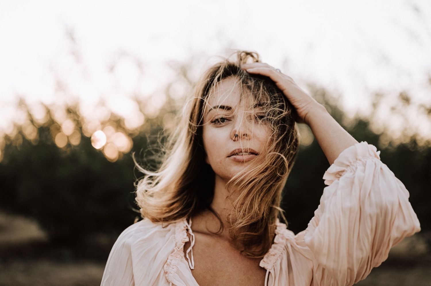 Ethereal sunset portrait with windswept hair and soft golden hour lighting.