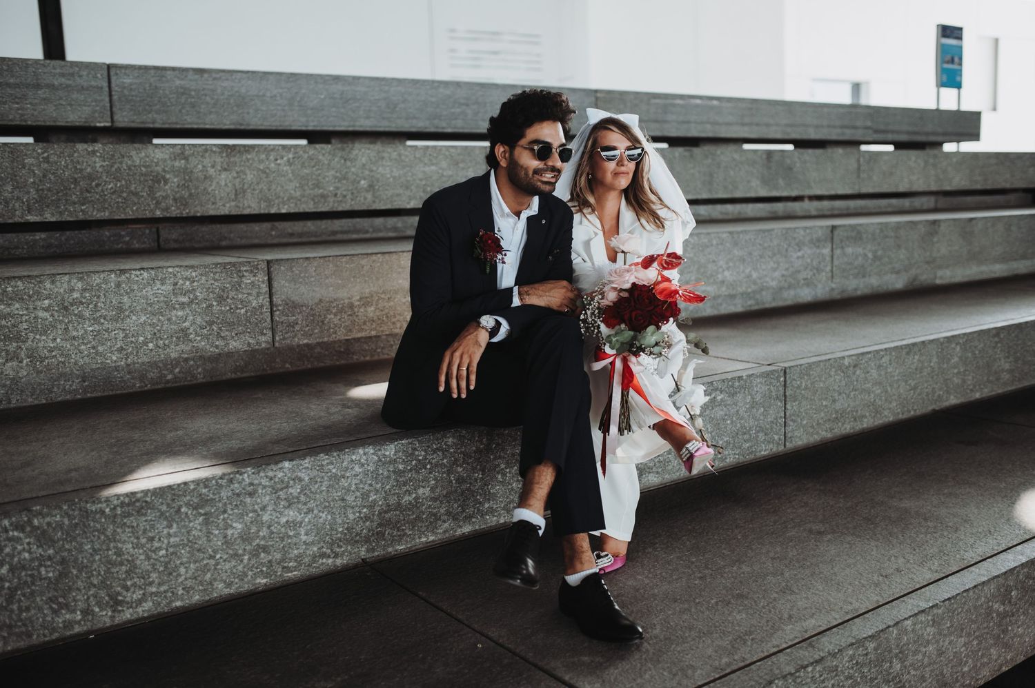 Couple sitting together on modern concrete steps with white flowers.