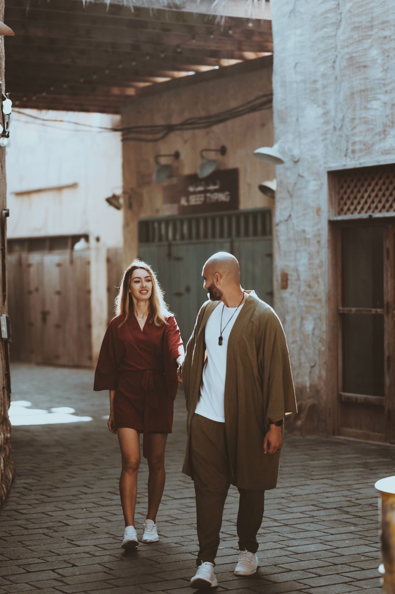 A couple walks together through a stone courtyard during sunset, creating a series of romantic silhouettes.