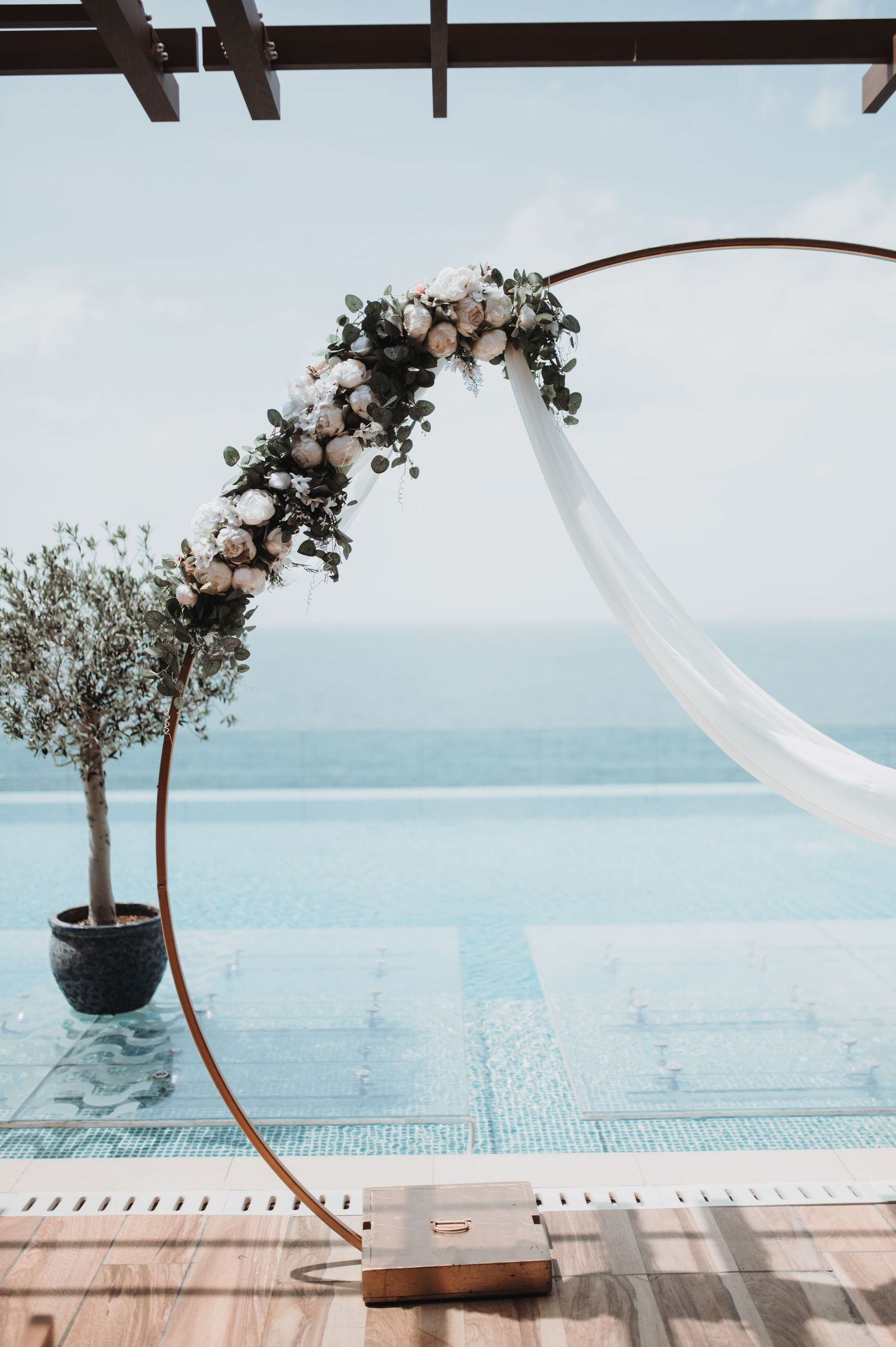 Floral arch overlooking ocean view at outdoor wedding venue.