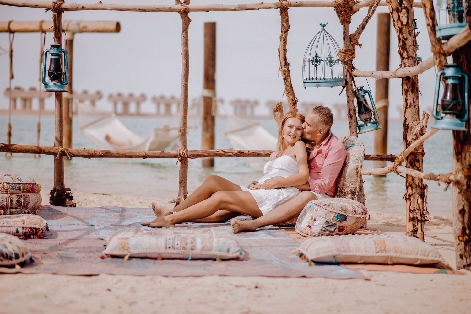 Beach photography session under wooden pier structures at sunset.