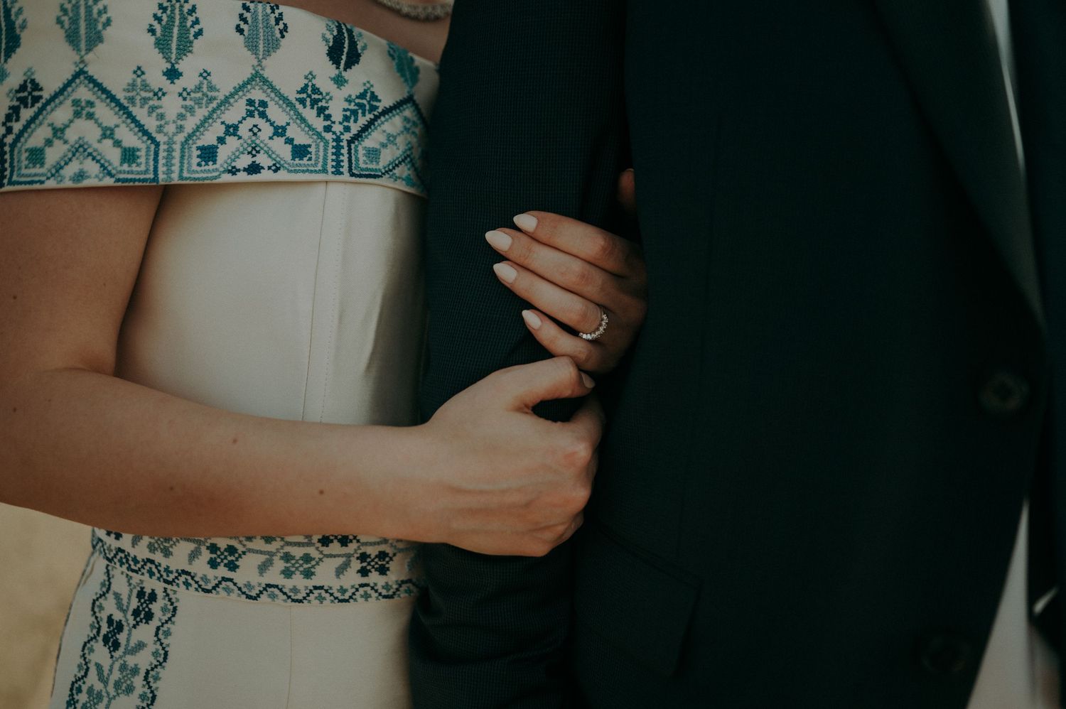 Close-up shot of couple holding each other against a blurred natural background.